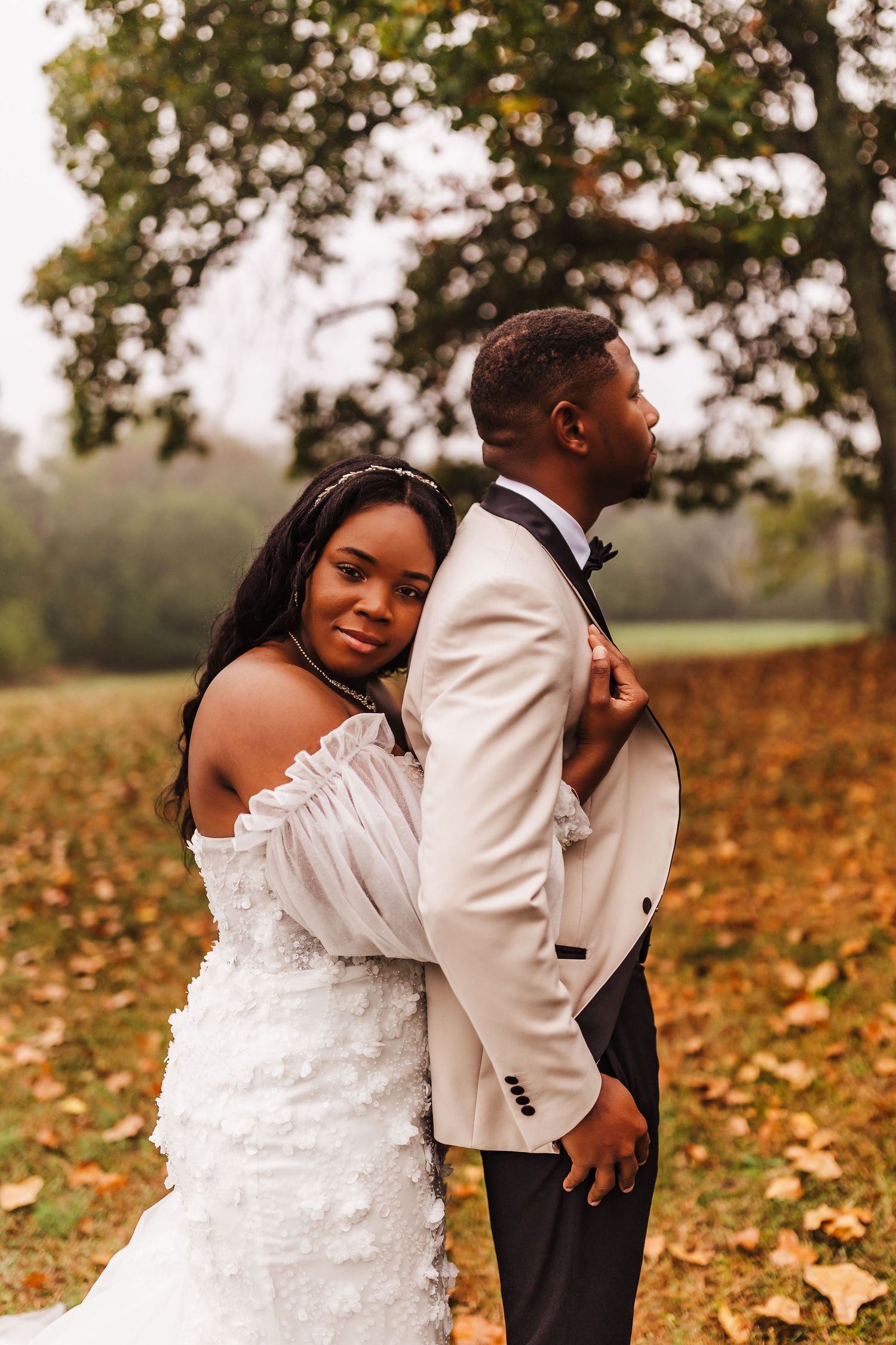An elegant autumn wedding portrait against a backdrop of falling leaves.