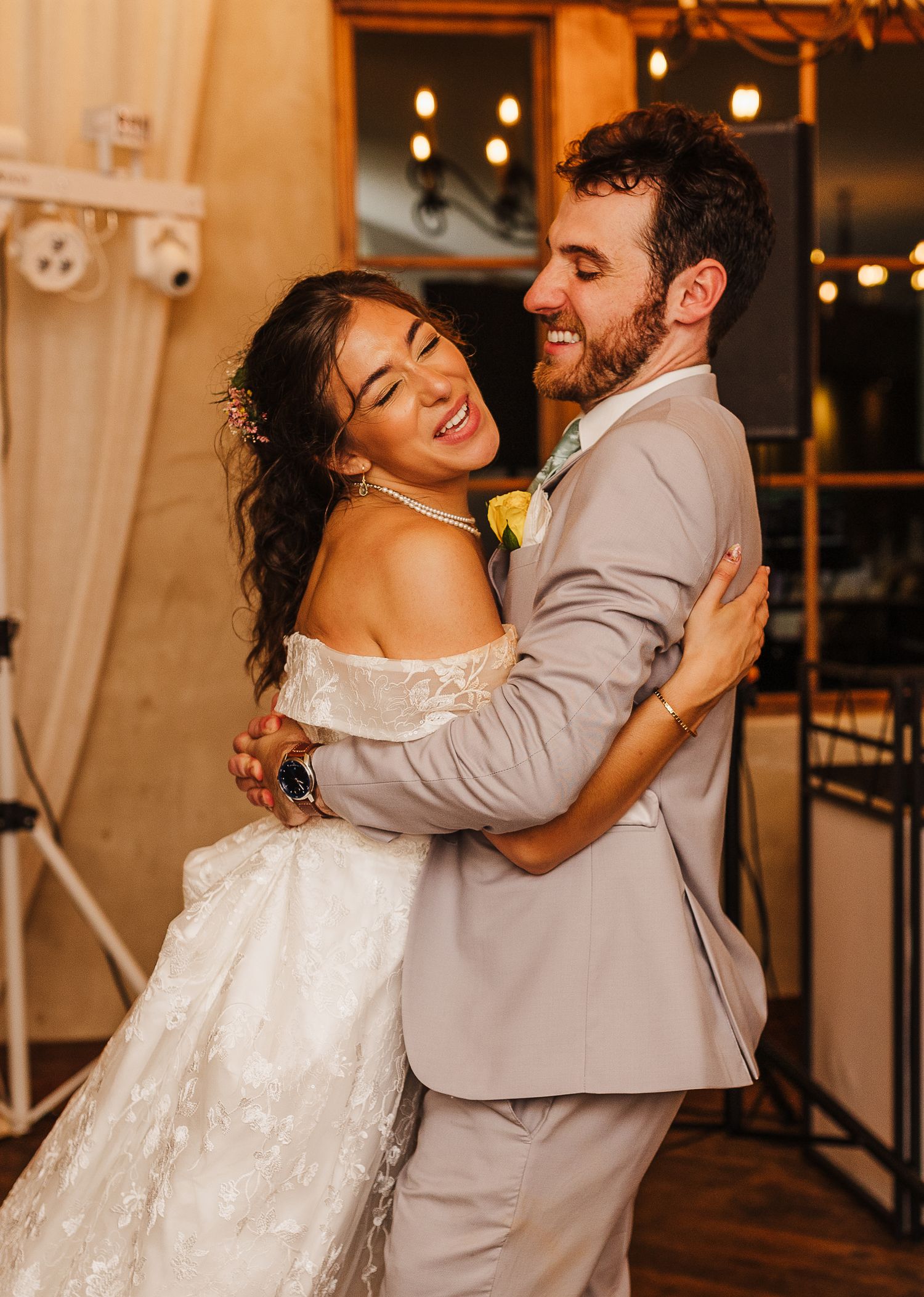 Joyful bride and groom share their first dance, laughing and embracing at their wedding reception.