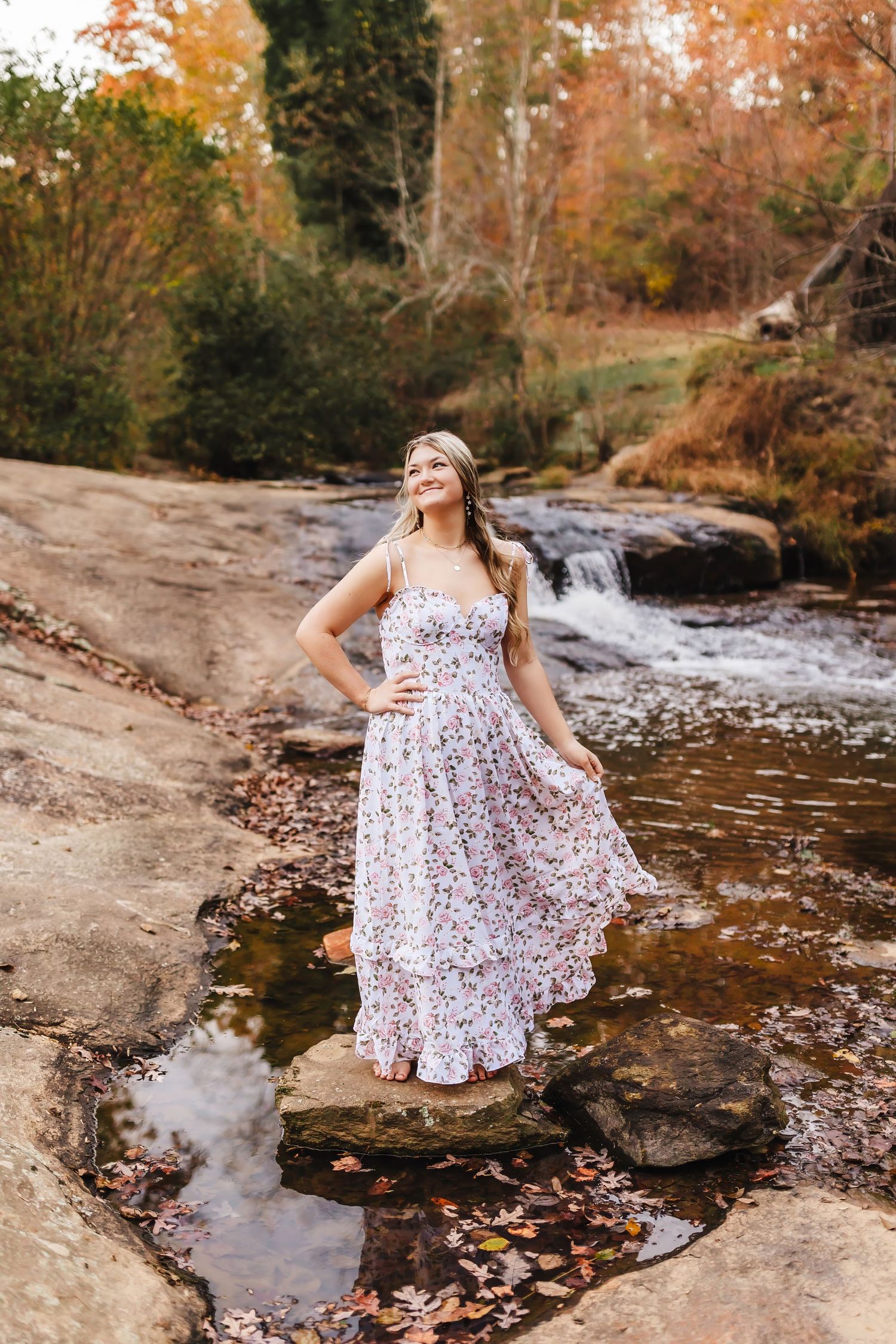 Senior portrait of a high school graduate standing by the creek during a fall session at Sells Mill Park.