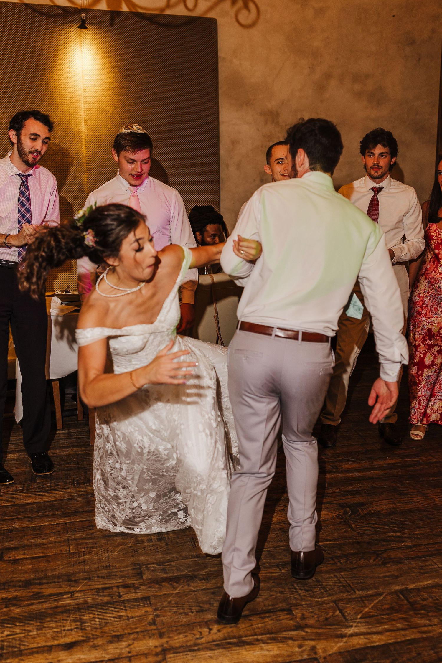 Bride and groom share a lively first dance at their wedding reception surrounded by guests.