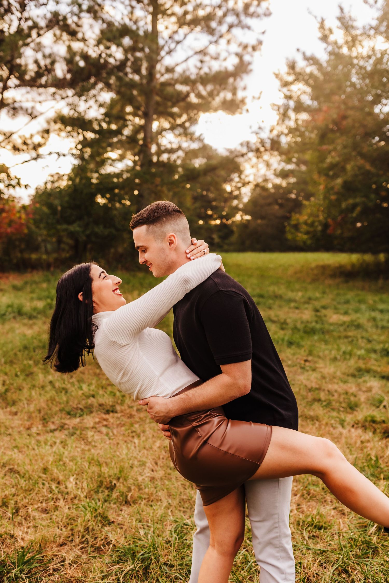 A playful couple embracing in a golden field at sunset.