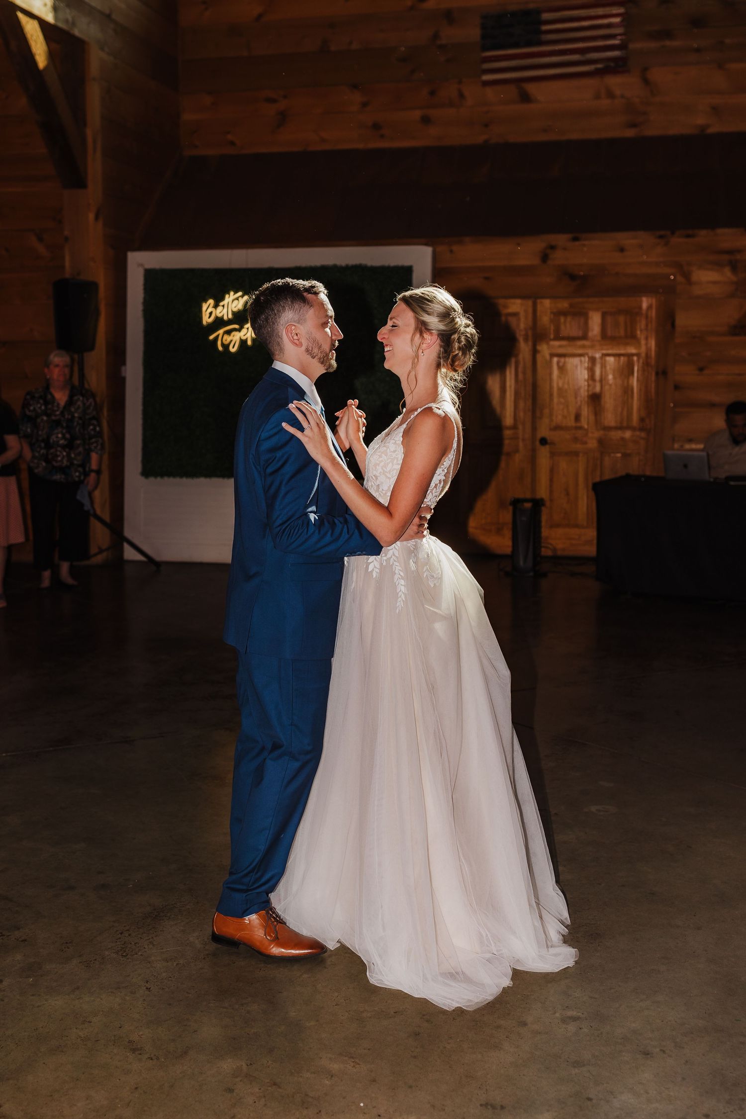 Bride and groom share their first dance at Walters Barn in Lula, Georgia, inside a rustic barn venue with an American flag visible.