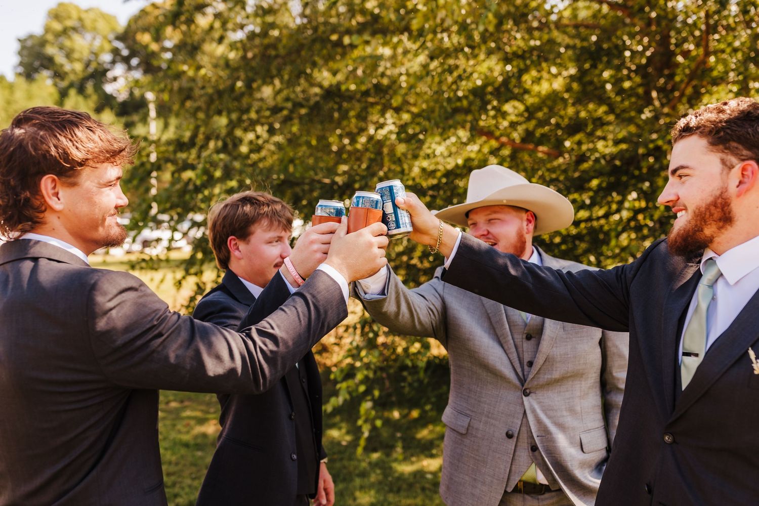 Groomsmen toast and celebrate with drinks in outdoor garden setting.