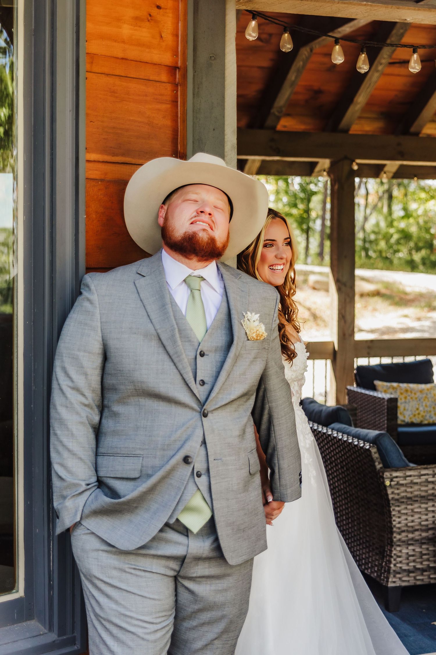 A wedding couple shares a joyful moment on a rustic wooden porch in North Georgia.