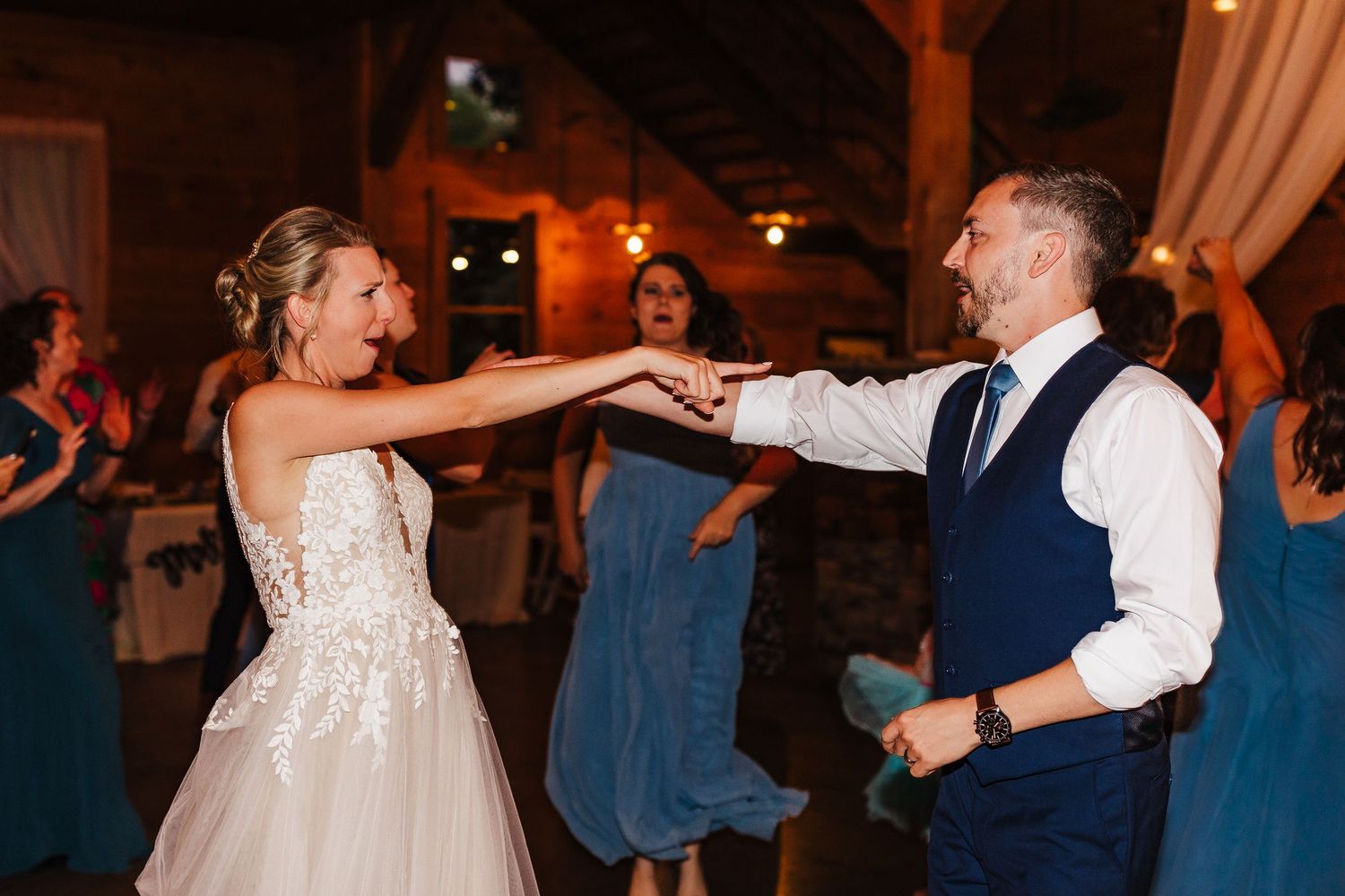 Wedding reception dance party at Walters Barn in a dimly lit rustic venue with guests in formal attire.