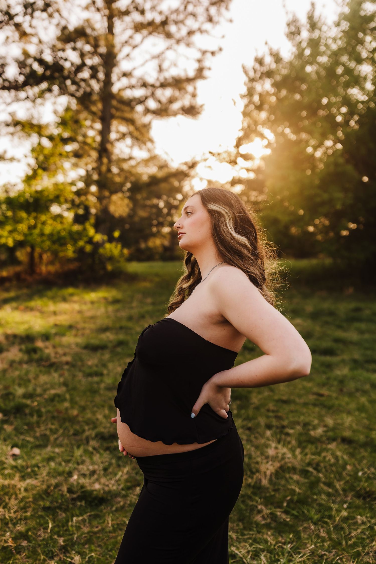 Golden hour maternity portrait of an expecting mother gazing toward the sunset at Little Mulberry Park.