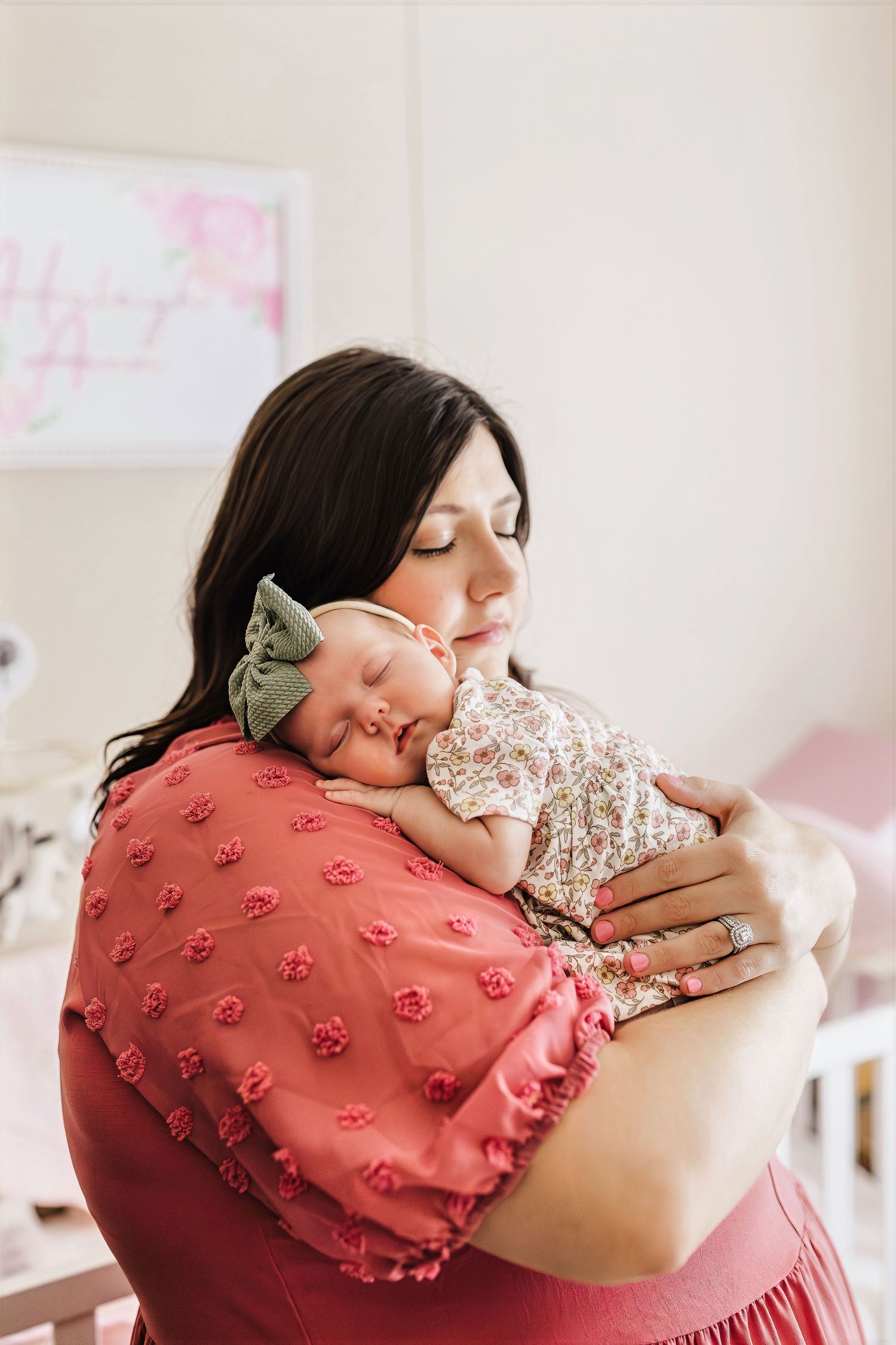 A tender moment captured as a person in a pink textured dress rests peacefully with a sleeping baby.