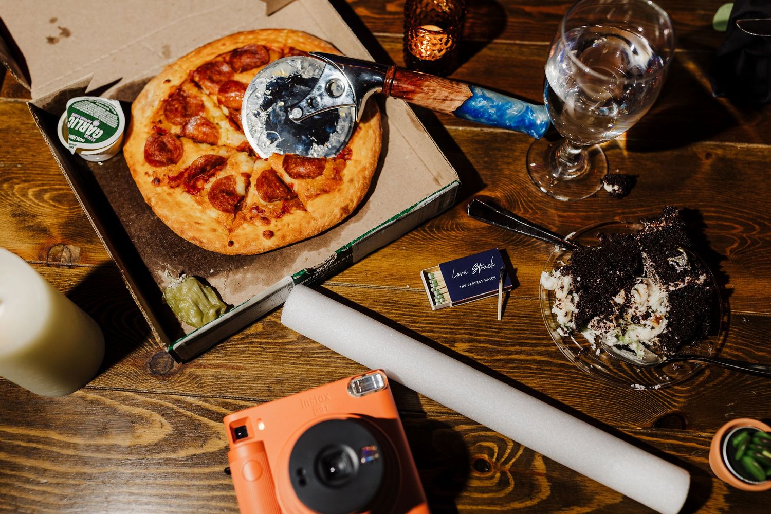 Pizza and drinks spread out on a wooden table at a wedding reception.