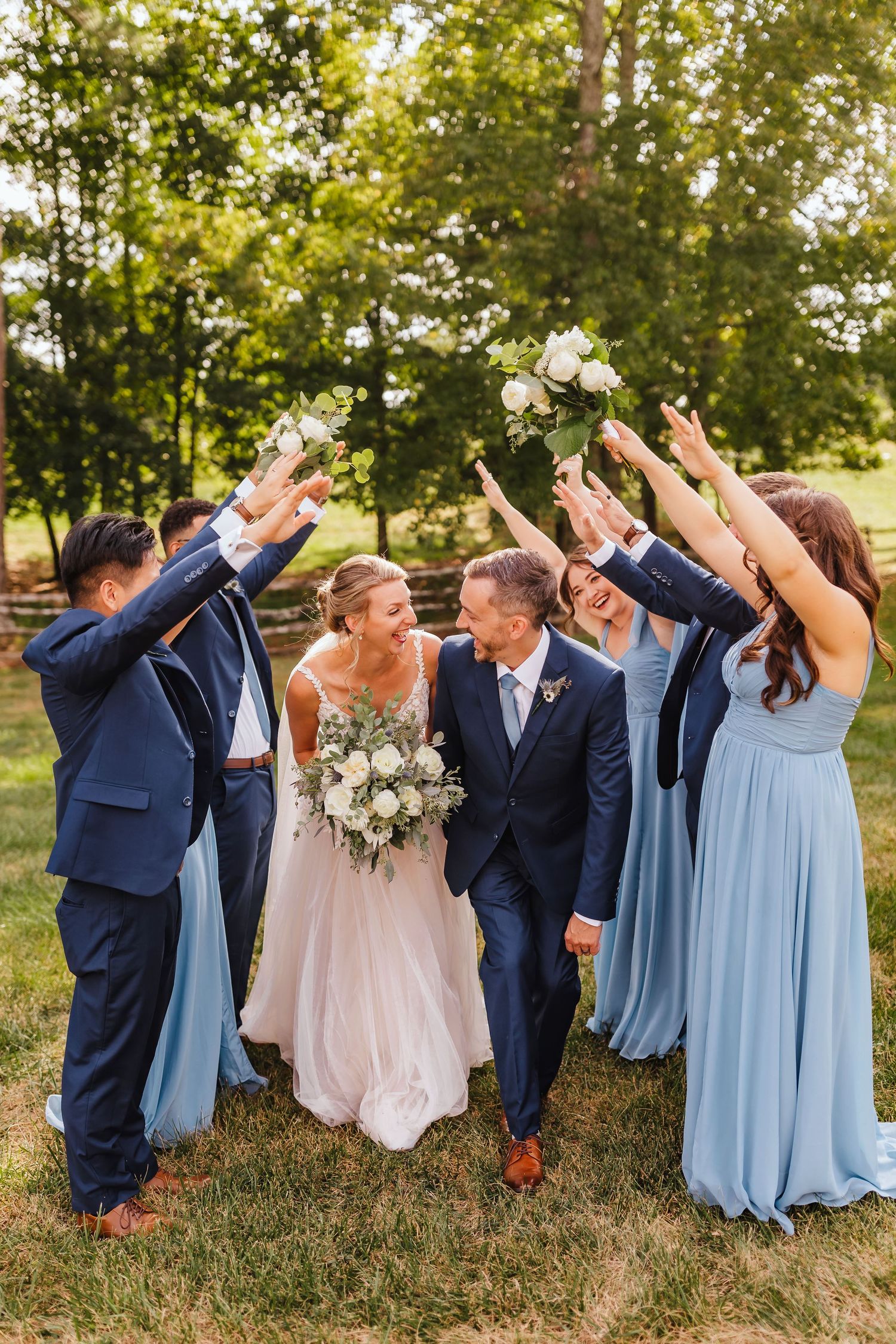 Bride and groom walking joyfully with their wedding party during an outdoor ceremony celebration at The Walters Barn.