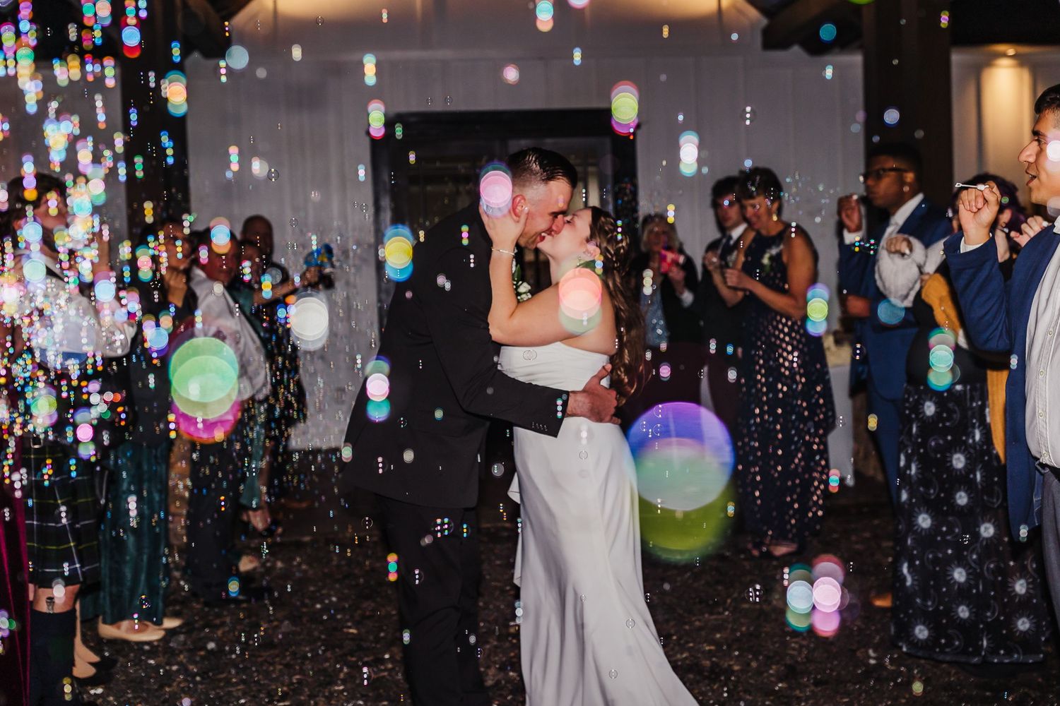 Wedding reception dance party with colorful lights and confetti in a dark venue.