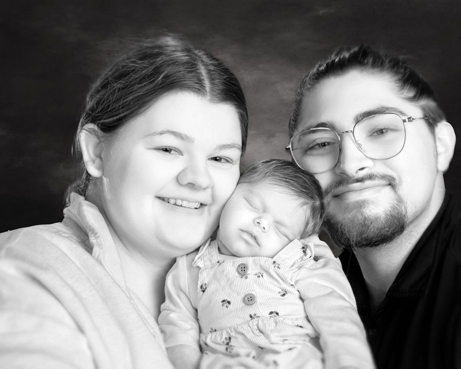 Black and white studio portrait of young couple with their sleeping newborn baby.