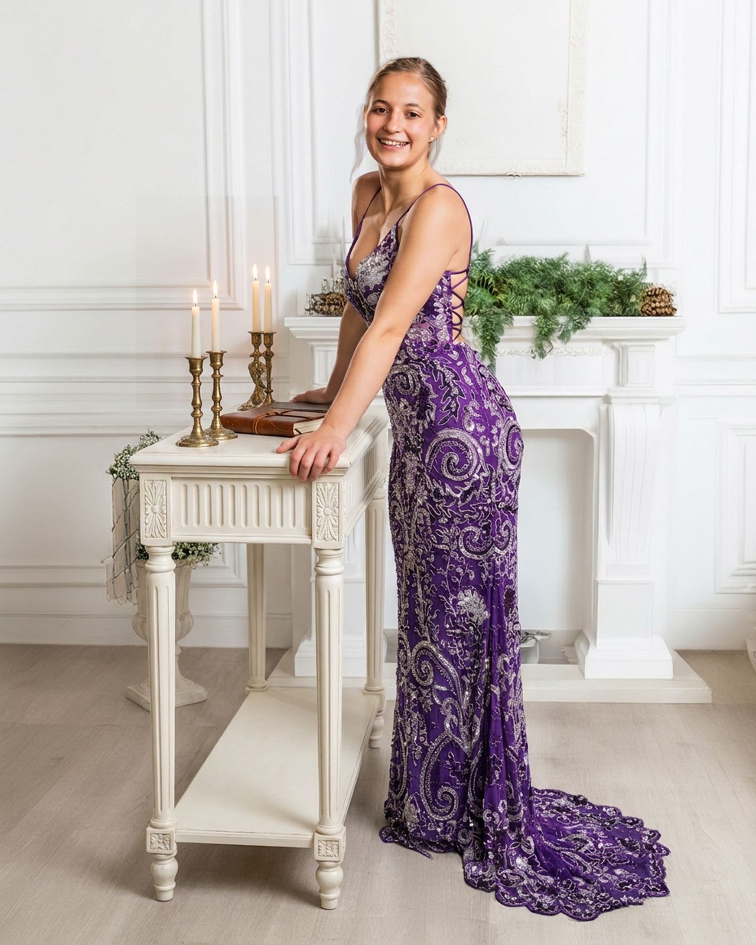 Smiling teen in purple sequin prom gown poses by candle-lit table indoors.