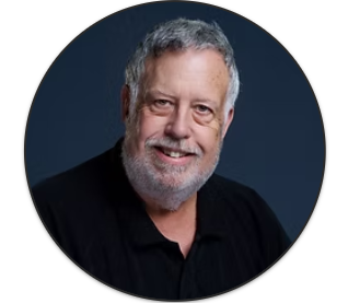 Professional headshot of smiling bearded man on dark background.
