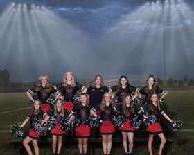 Lakeshore cheerleaders in red and black uniforms pose with pom-poms on outdoor bleachers in 2022.