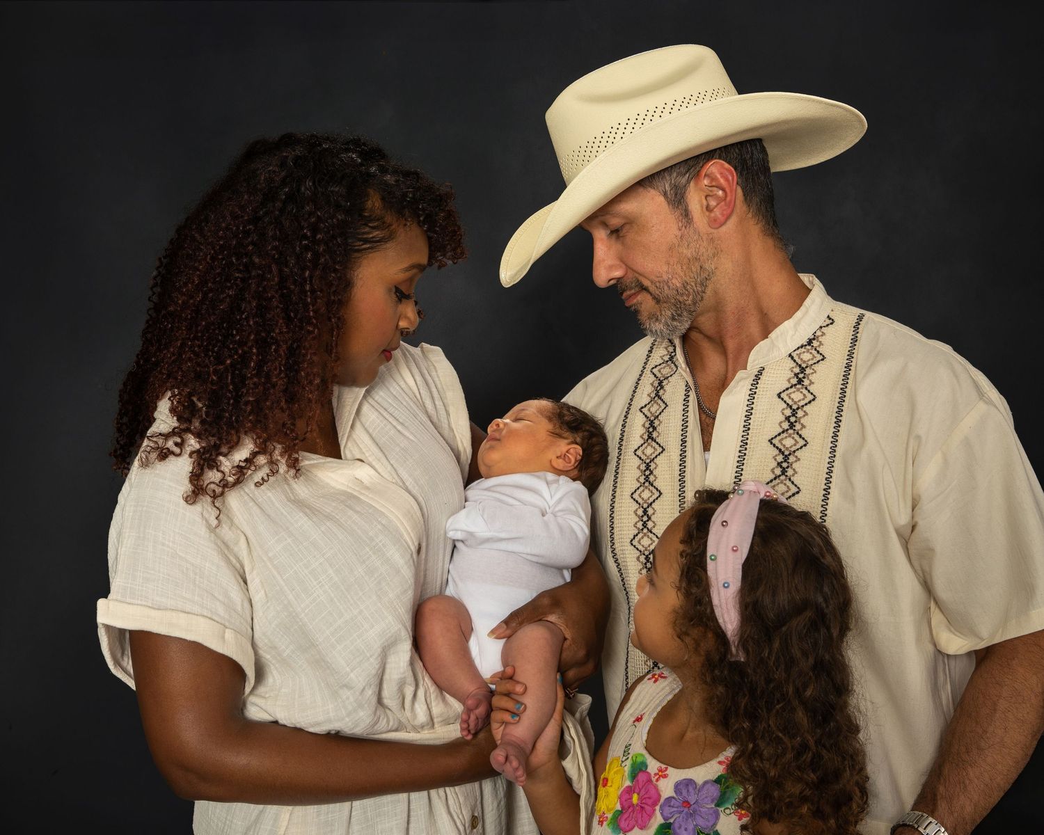Interracial family with parents and two children sharing a tender moment in studio portrait.