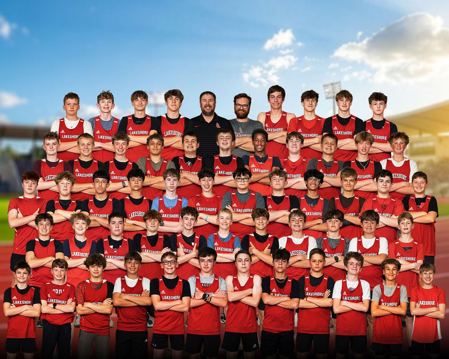 Large boys soccer team portrait in red uniforms posing in three rows outdoors.
