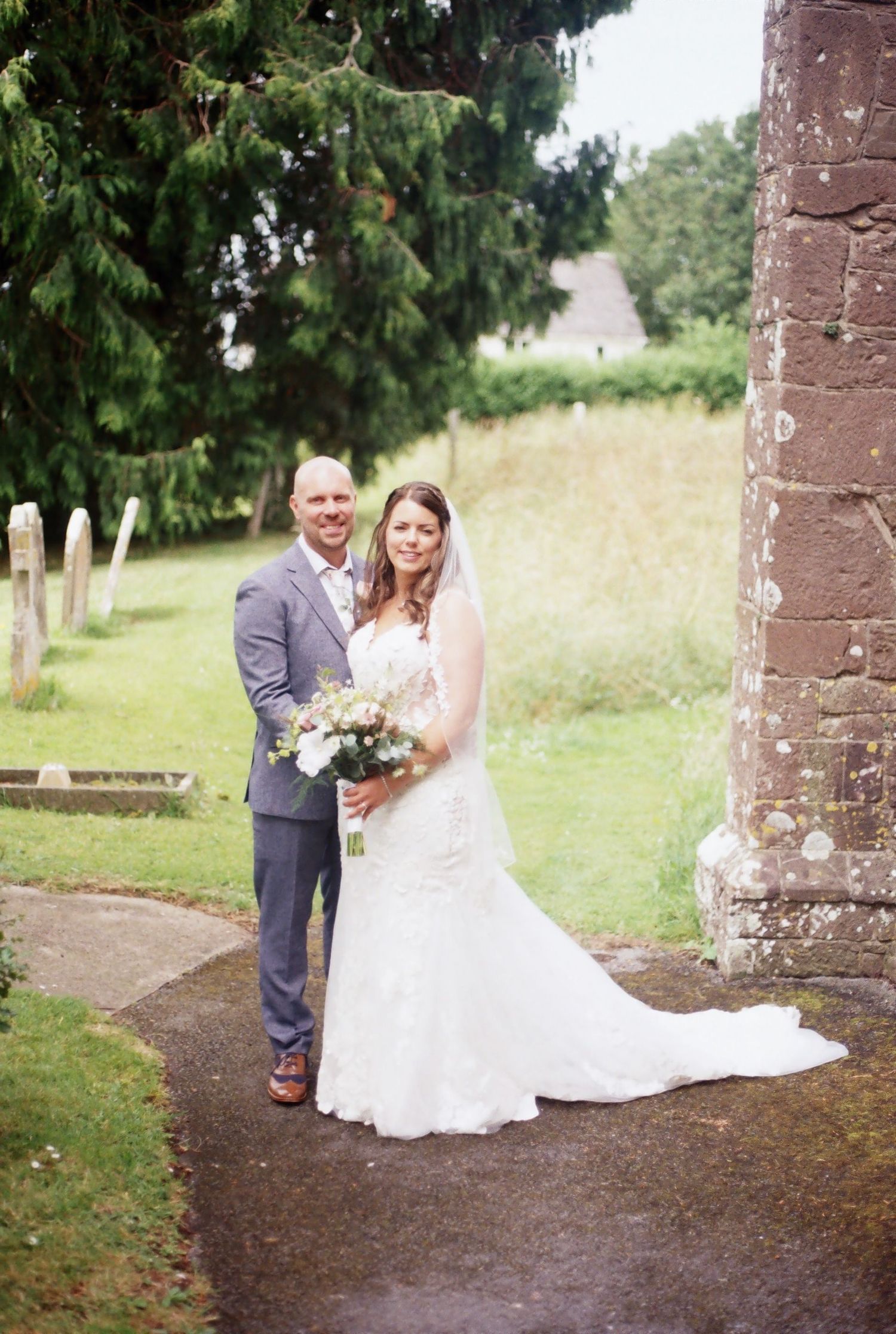 bride and groom next to the church they married in, photographed on 35mm film camera.