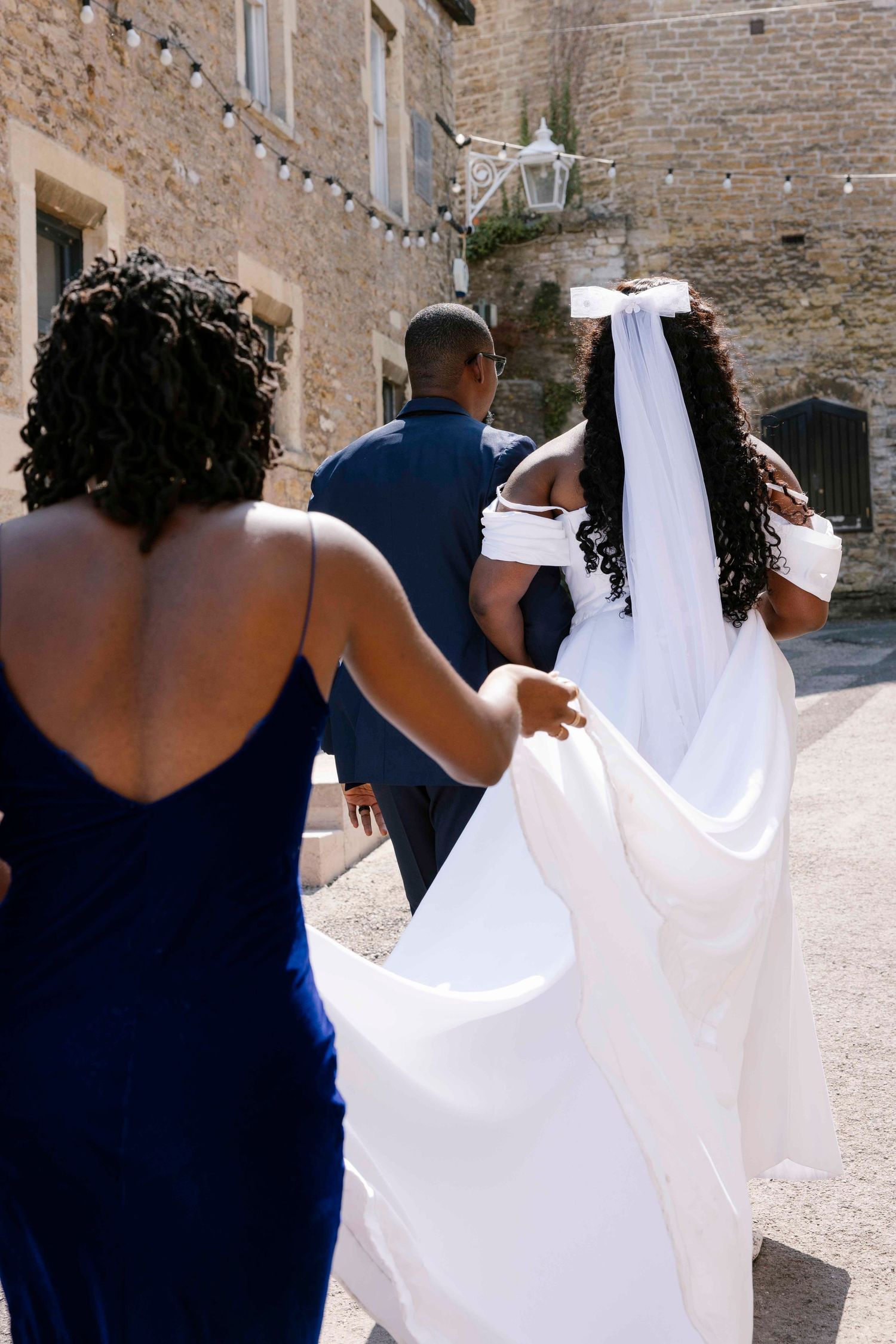 Best friend, Maid go honour carrying the Brides dress as she walks with groom to have a moment quite after wedding