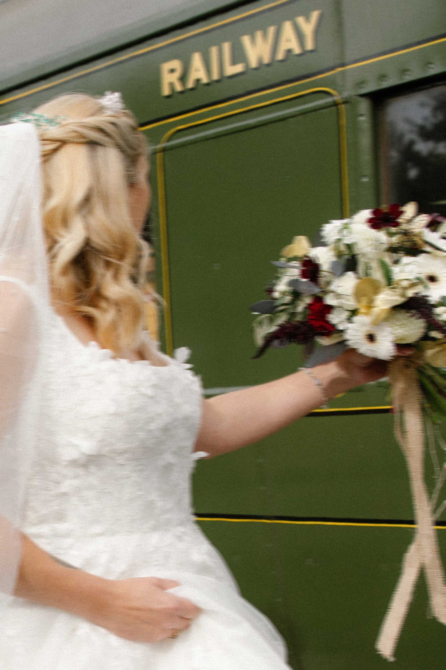 bride walking to the carriage where she will get married, featuring the railway work on the side o the train