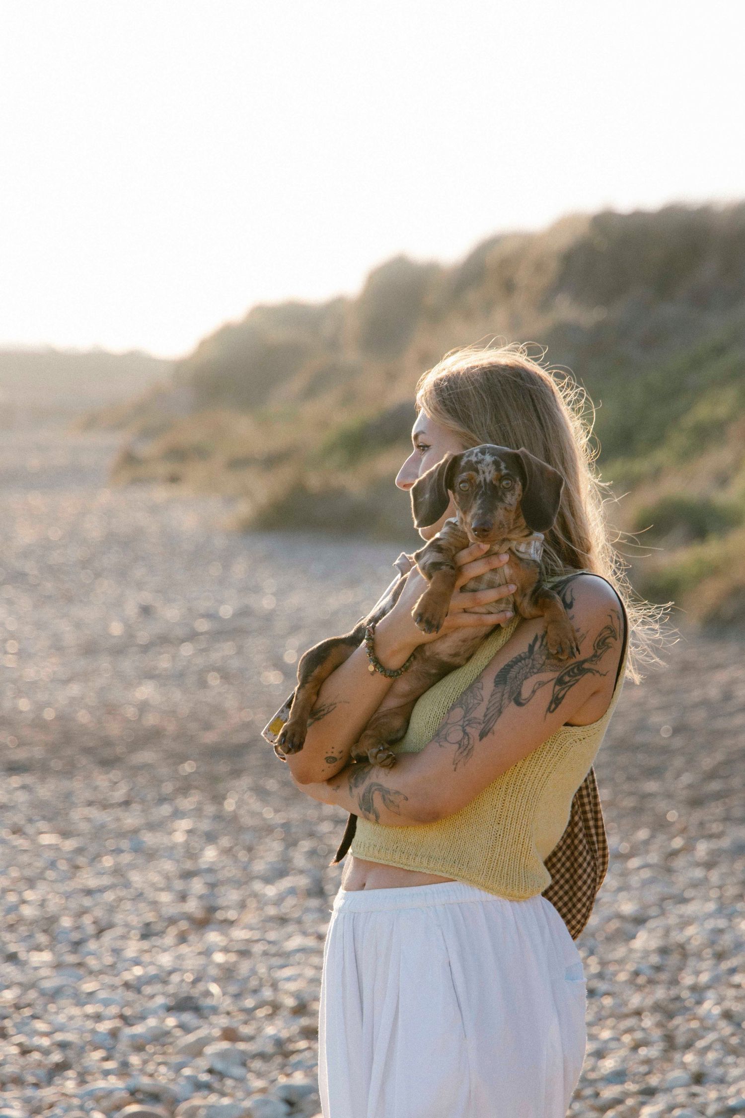 Woman holding her dog on Hengistbury head beach
