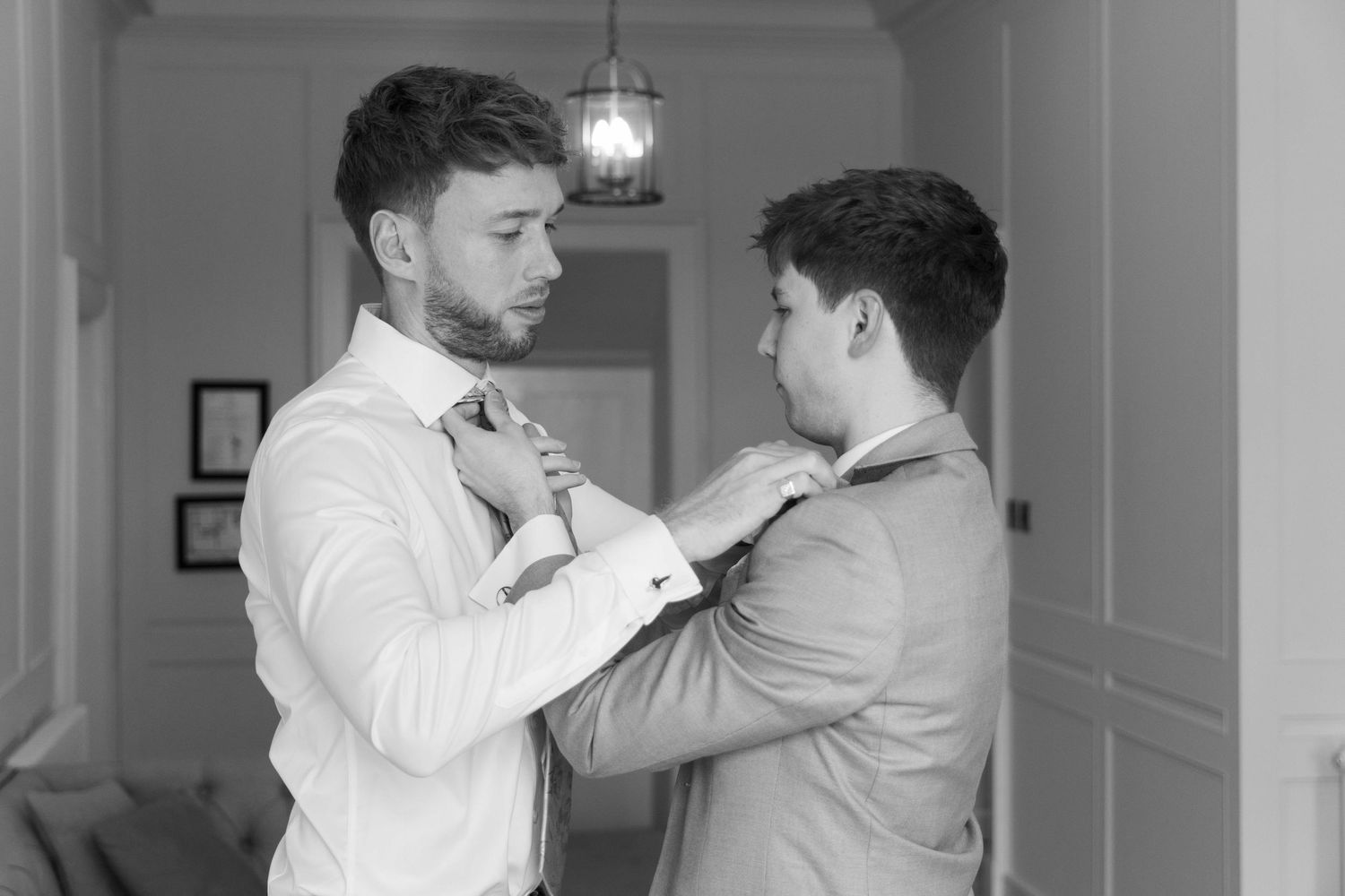 Two groom helping fix each other ties in the moments before they marry
