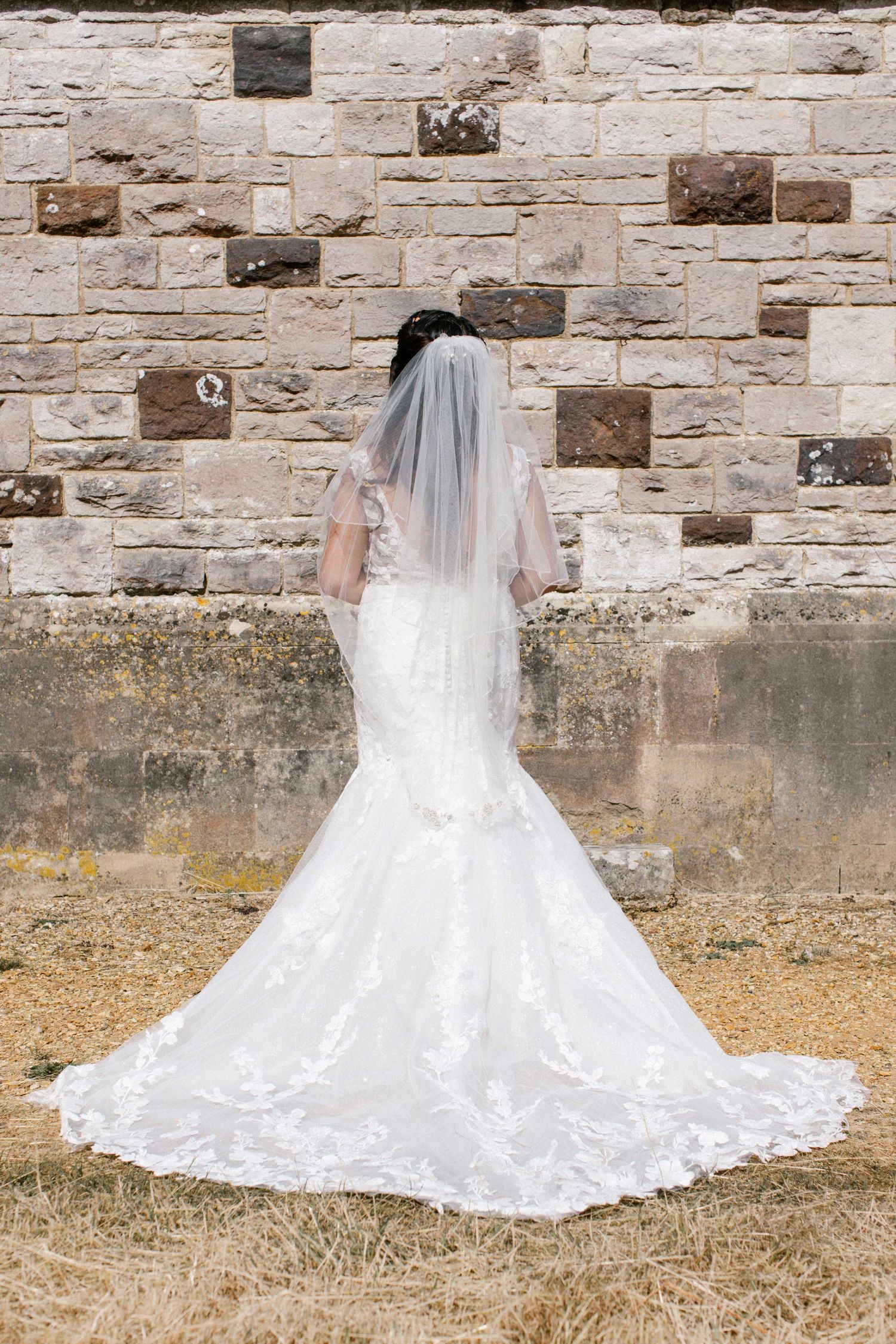 Bride showing off the back of her dress while she waits for family to join her for images at the St Stephen's, Kingston
