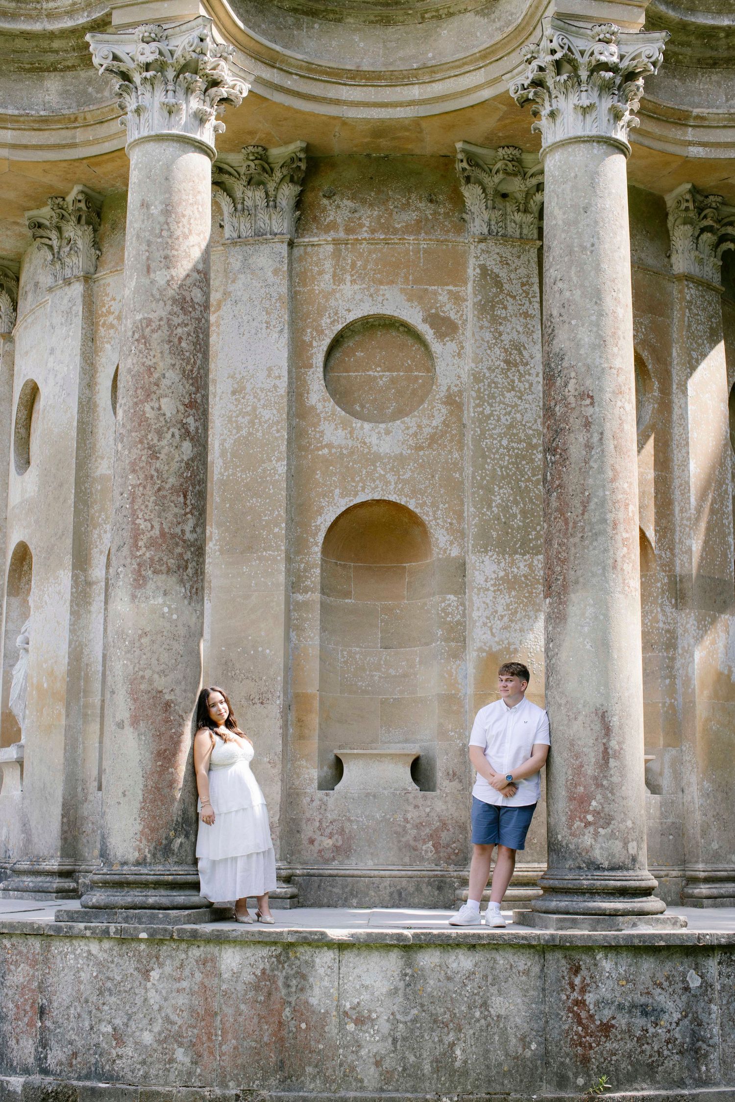 Newly engaged couple leaning against pillars at Temple of Apollo