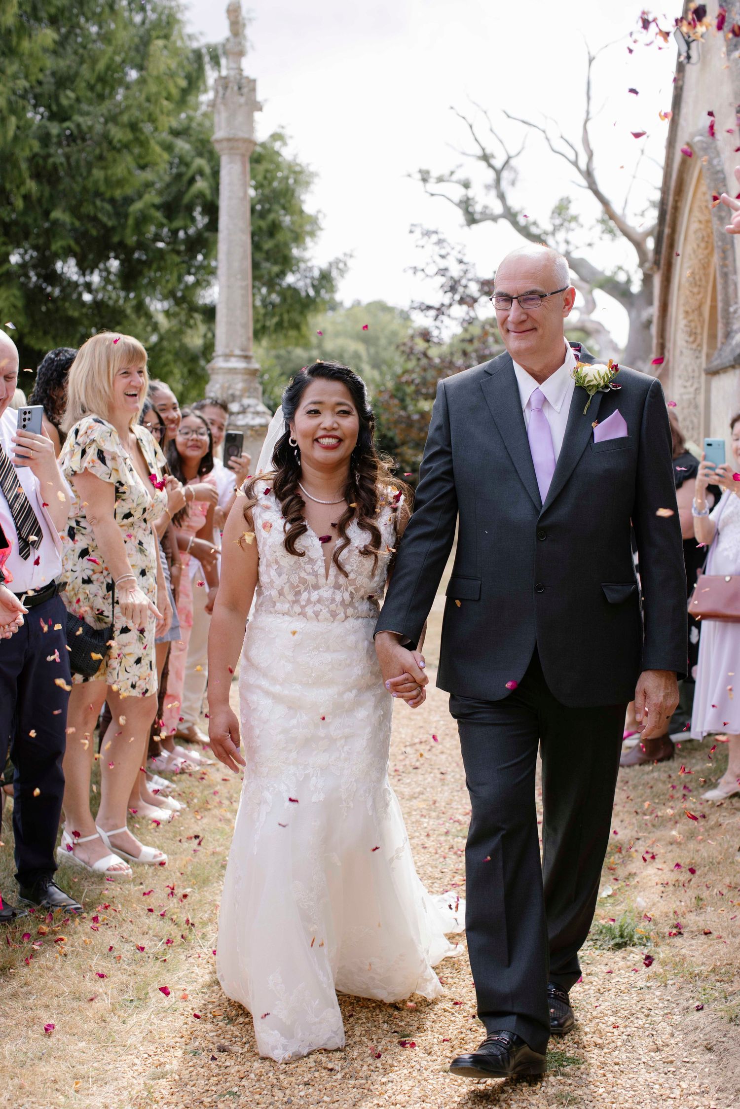 Bride and groom in confetti as they walk down through a line of family and friends at St Stephen's, Kingston