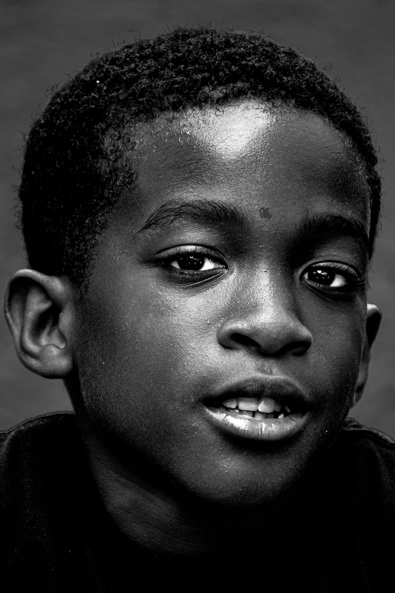 Black and white portrait of a young boy with expressive eyes looking at the camera.