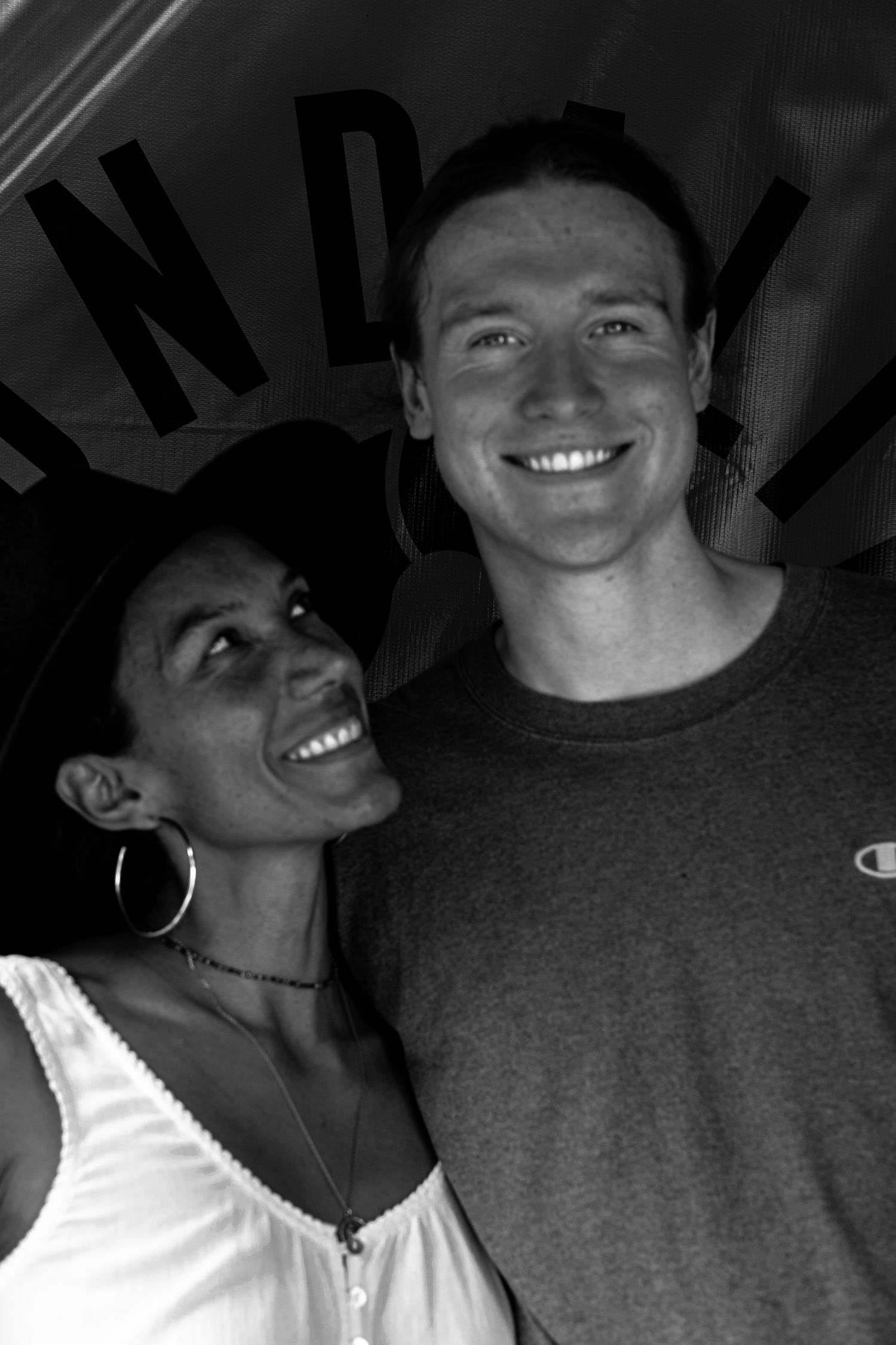 Black and white photo of a smiling interracial couple posing together indoors.