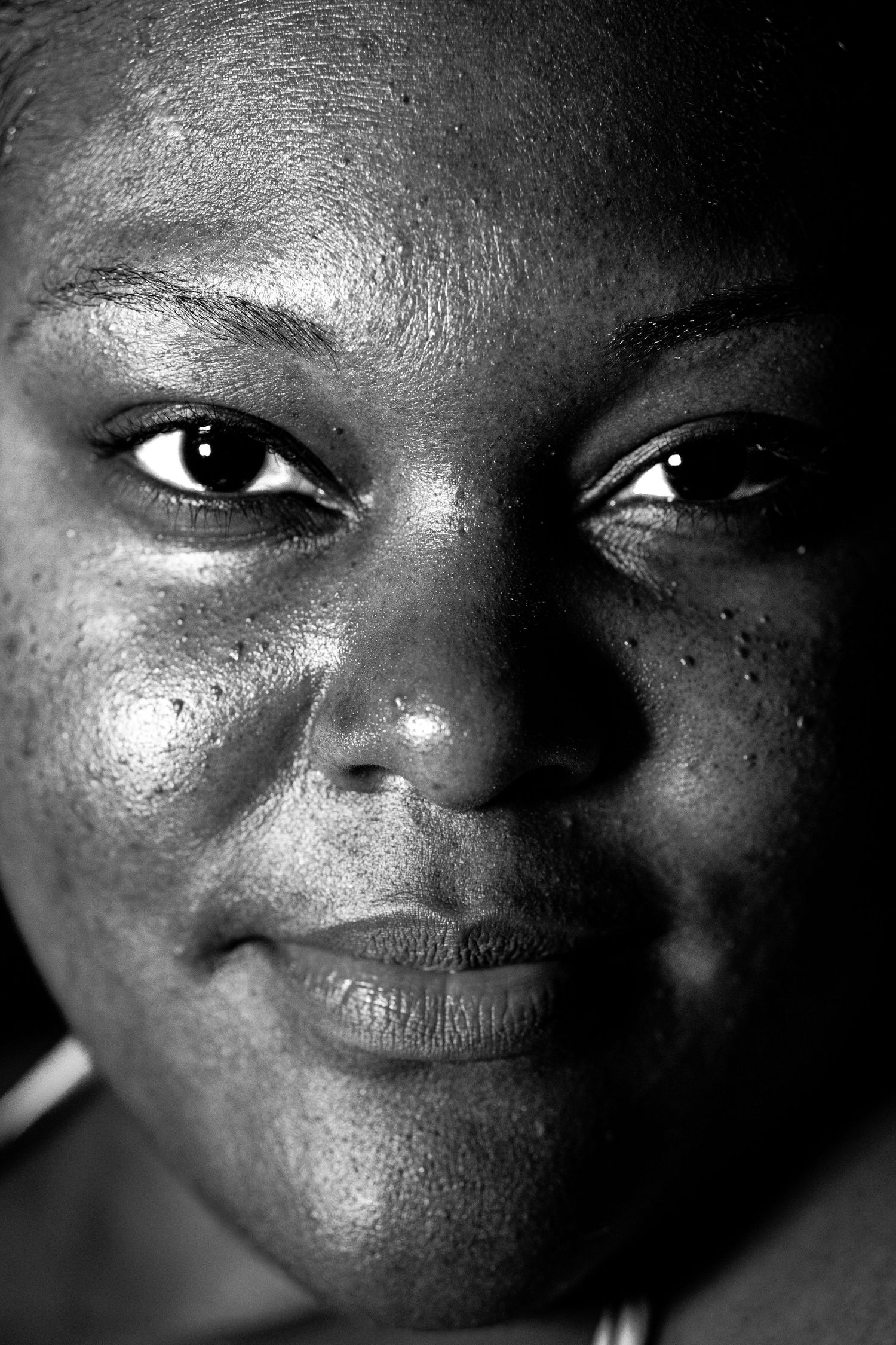 Close-up black and white portrait of a woman with bright eyes and a gentle smile.