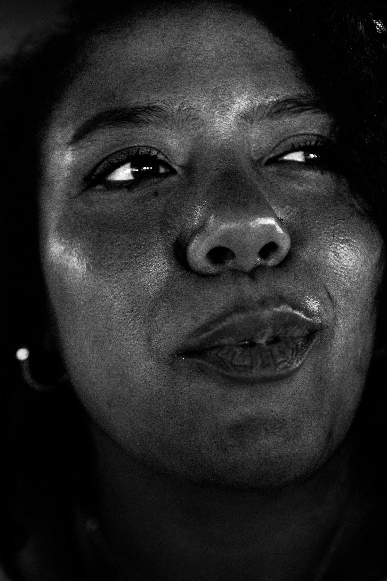 Close-up black and white portrait of a woman with a subtle smile looking upward.