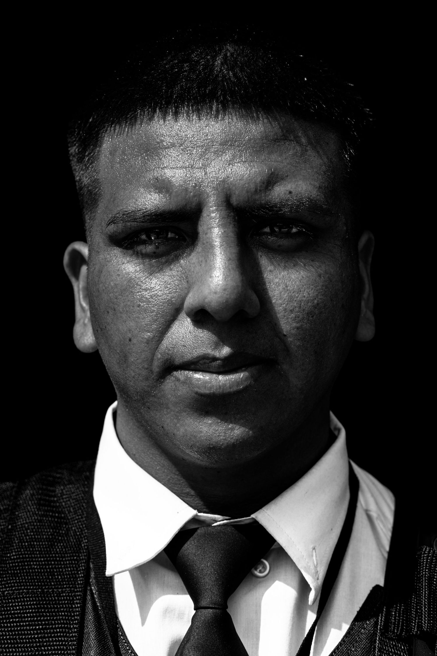 Dramatic black and white close-up portrait of a man in a suit and tie with intense expression.