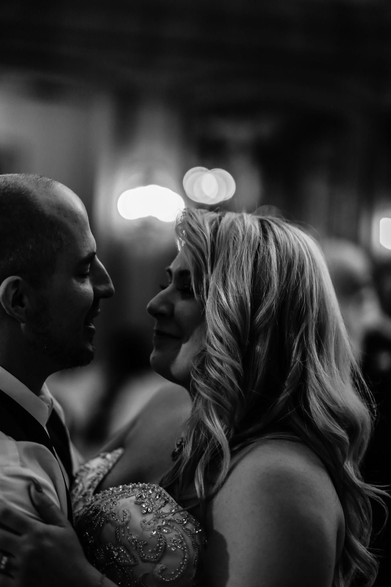 Bride and groom share an intimate moment during first dance in black and white.
