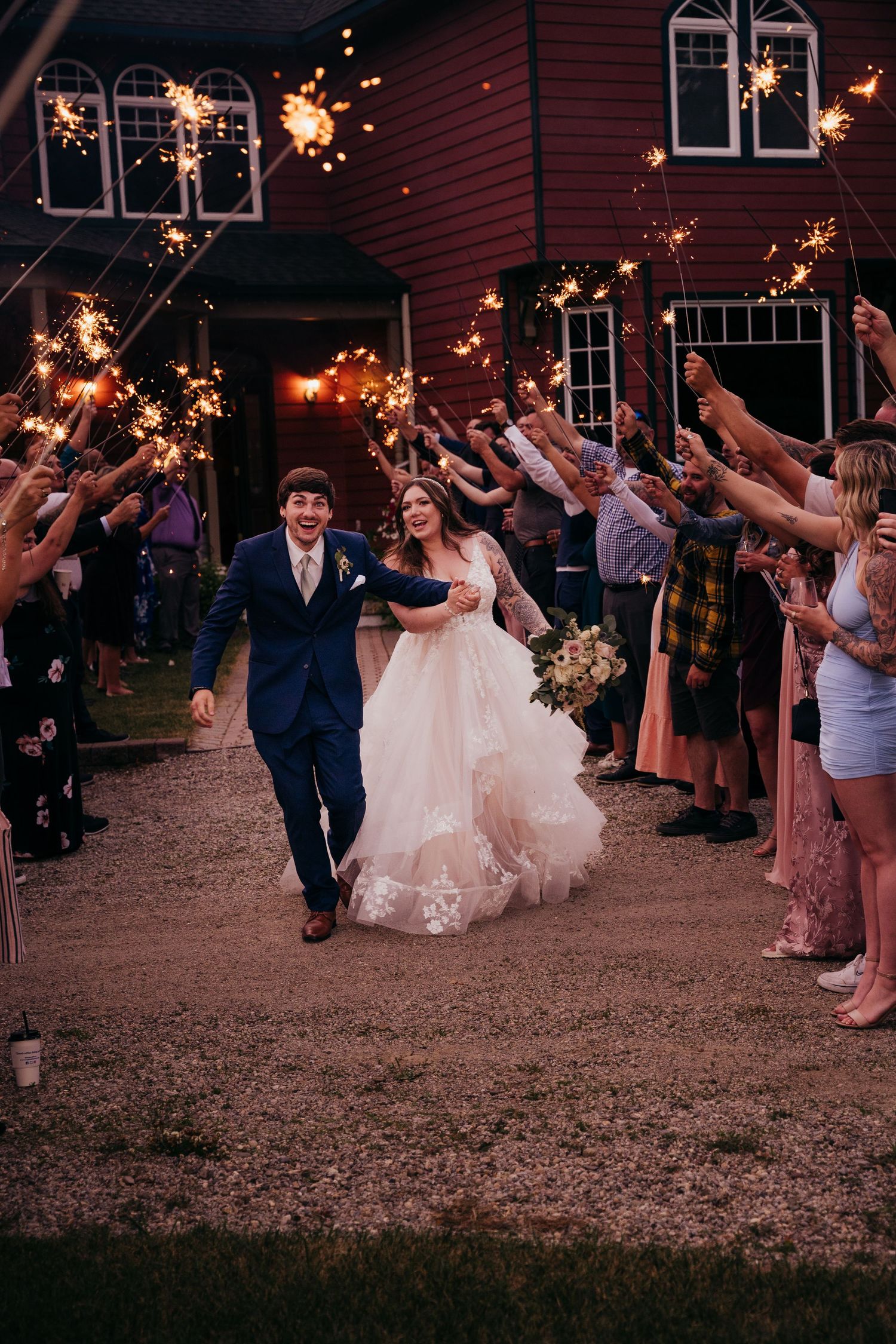 Newlyweds run joyfully through a sparkler tunnel as wedding guests celebrate their grand exit.