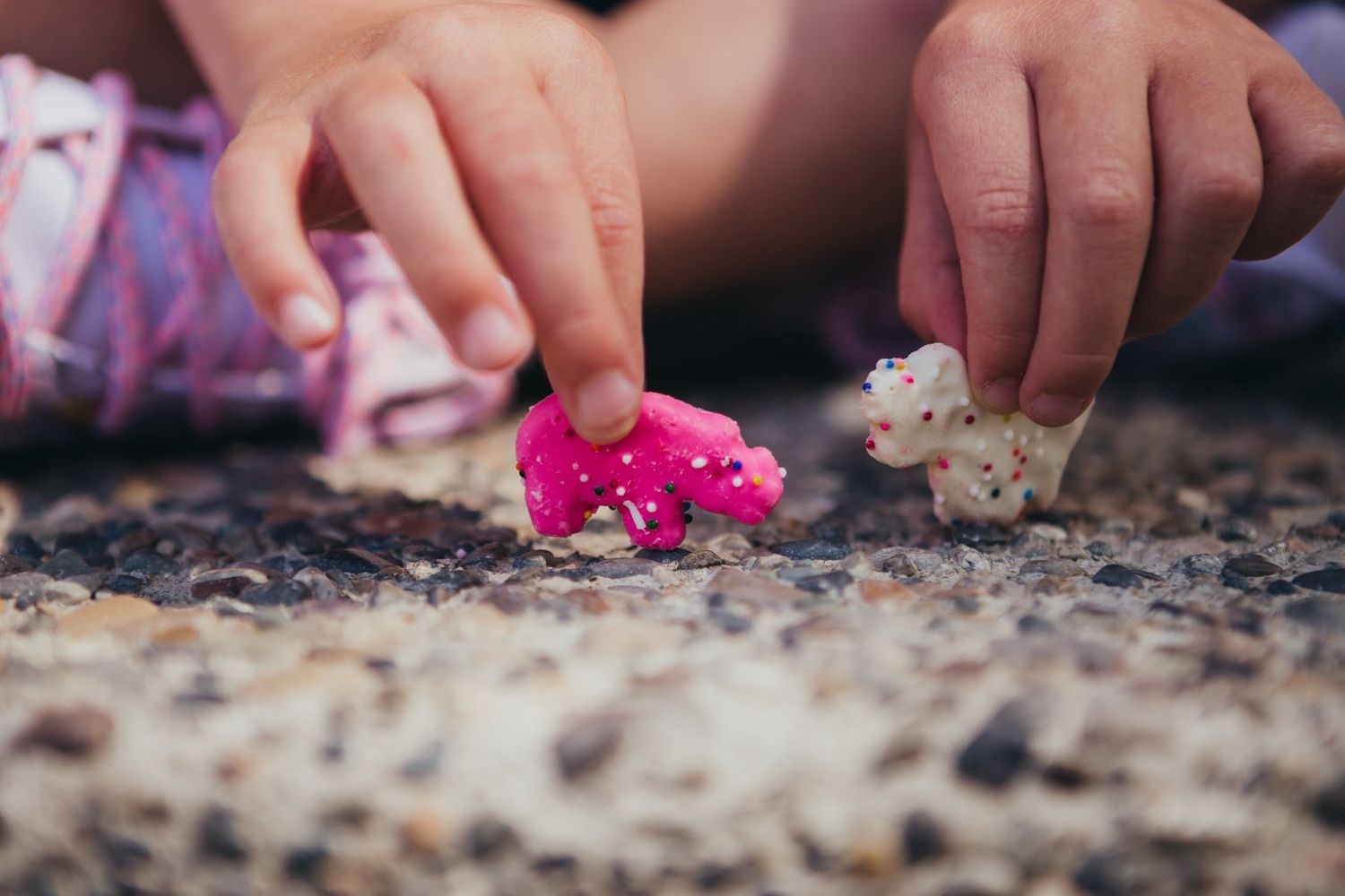 Close-up of child and adult hands playing with small pink and white figurines.