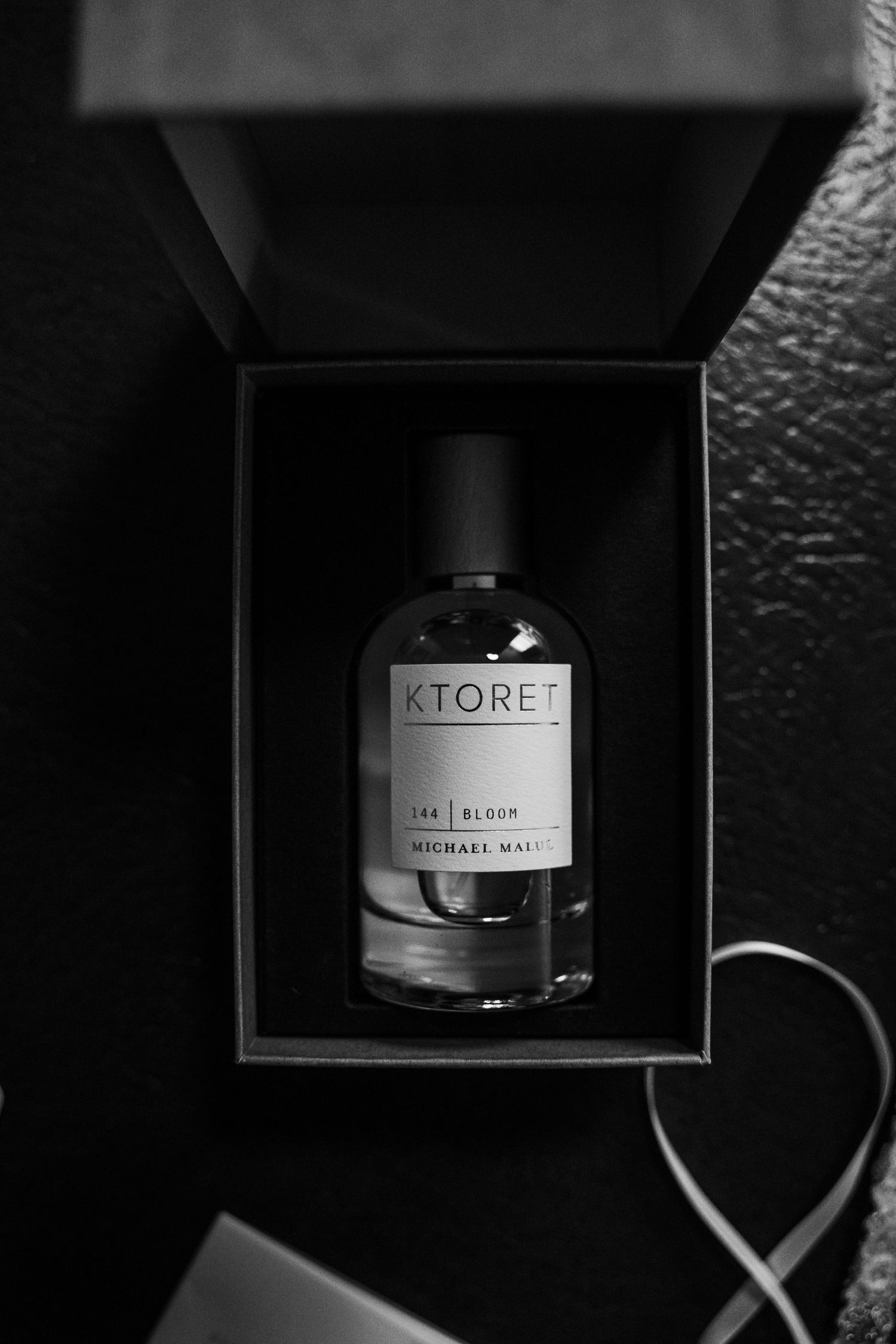 Black and white close-up of Ktoret Bloom by Michael Malul perfume bottle in luxury gift box.
