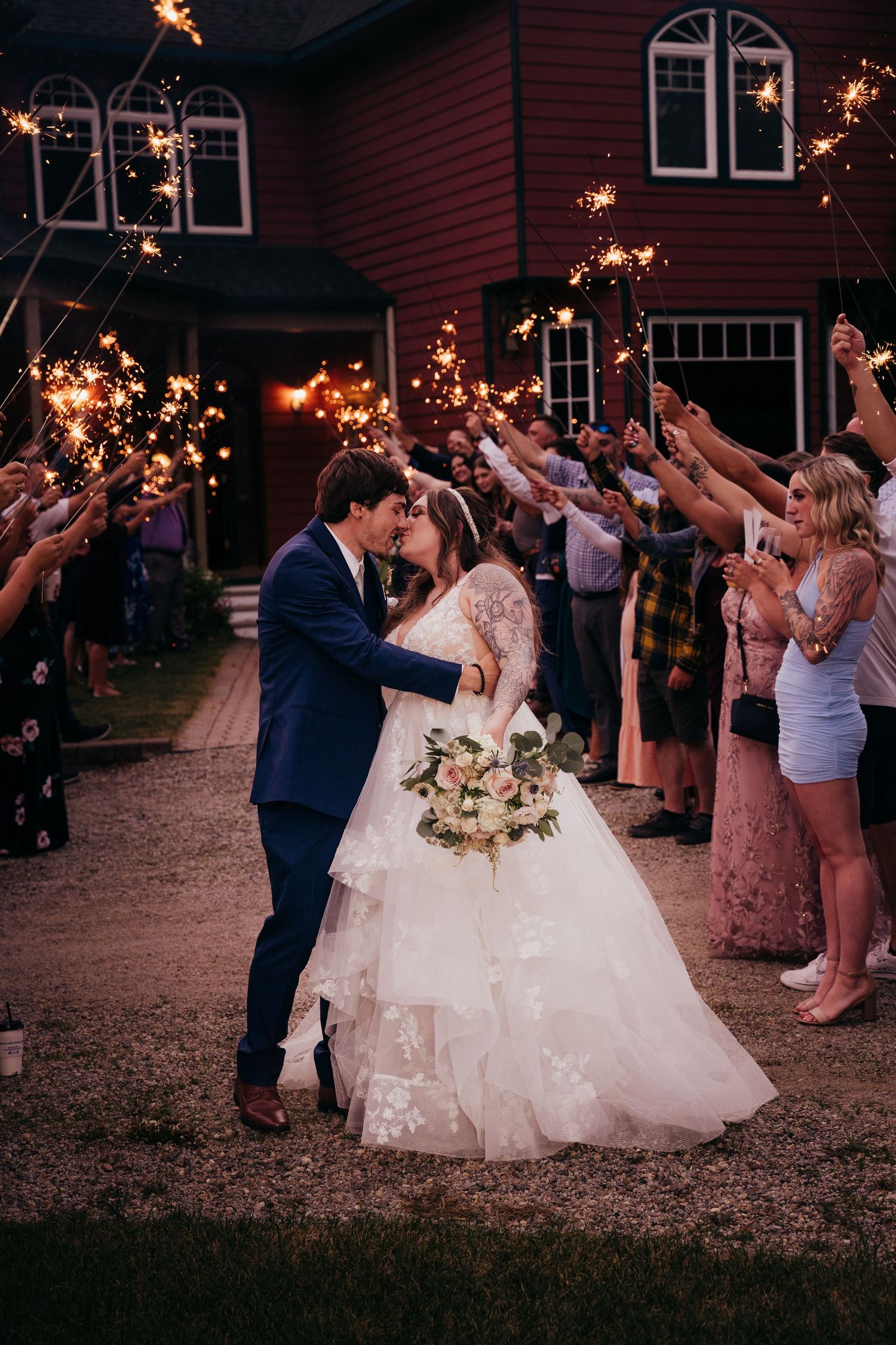 Bride and groom share a romantic kiss during a sparkler send-off at their evening wedding reception.