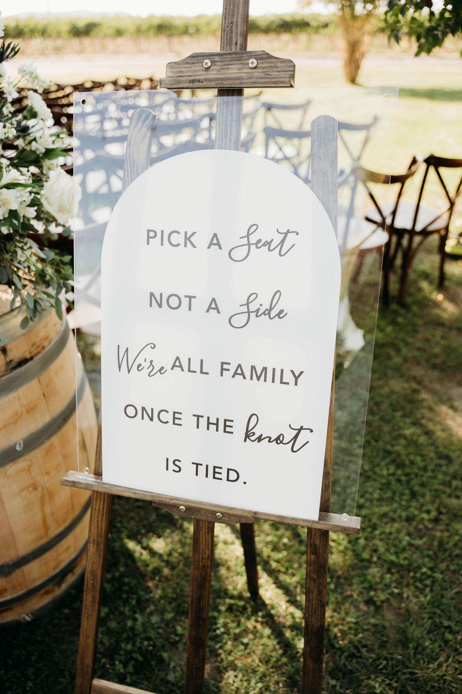 Wedding ceremony sign on easel reading Pick a Seat Not a Side We're All Family Once the Knot is Tied.