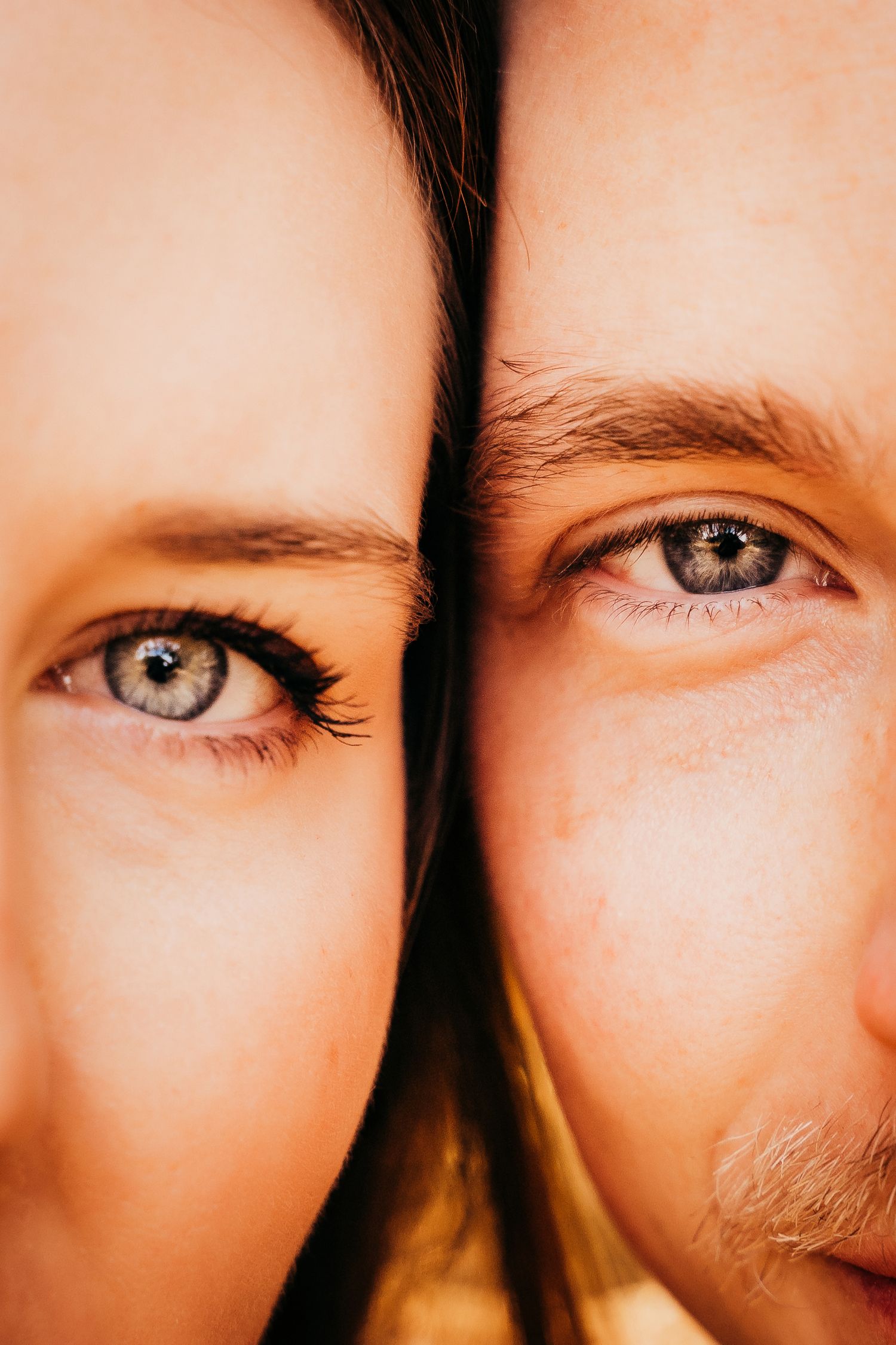 Close-up portrait of a couple with blue eyes pressing their faces together side by side.
