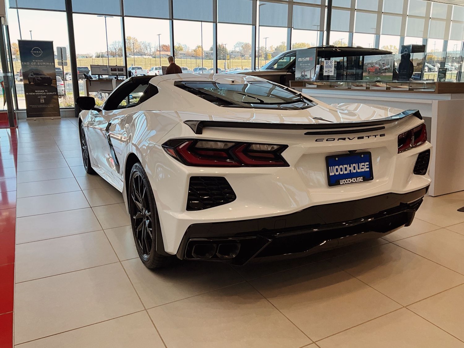 White Chevrolet Corvette C8 sports car displayed on showroom floor at Woodhouse dealership.