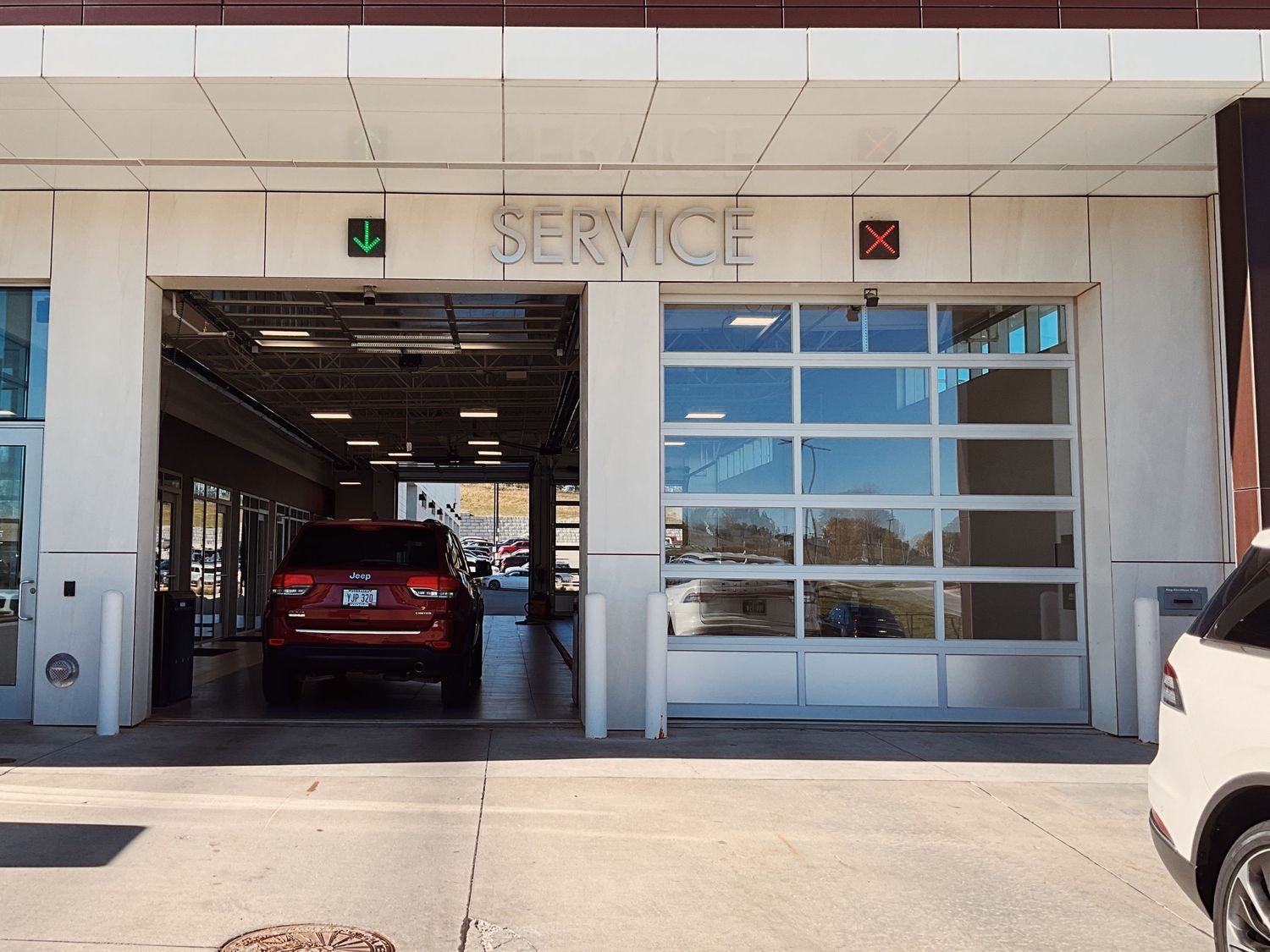 Car service center entrance with open bay doors, a red SUV inside, and a SERVICE sign above the garage.