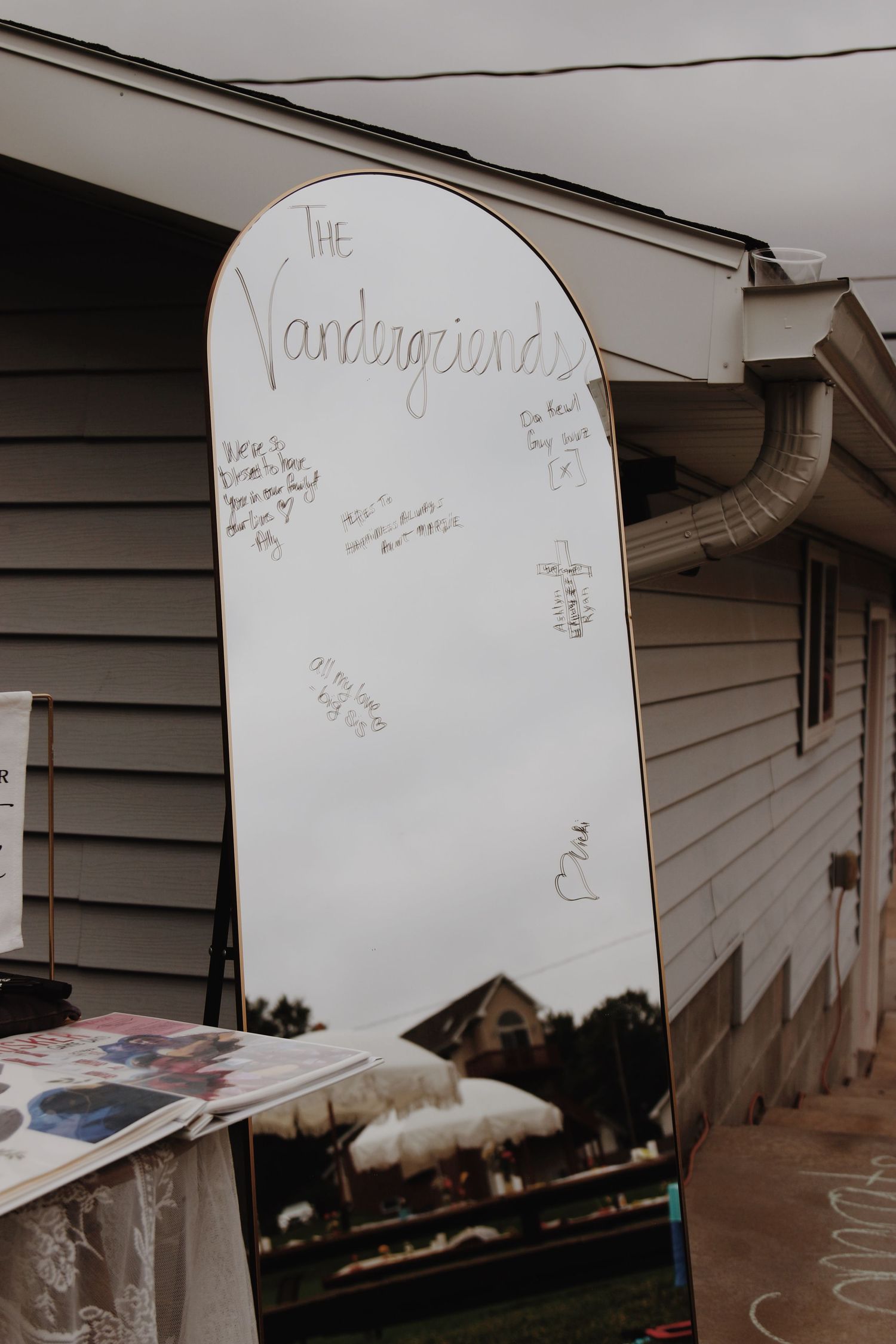 White snowboard guest book leaning against a house, signed by wedding guests for the Vandergriend family.