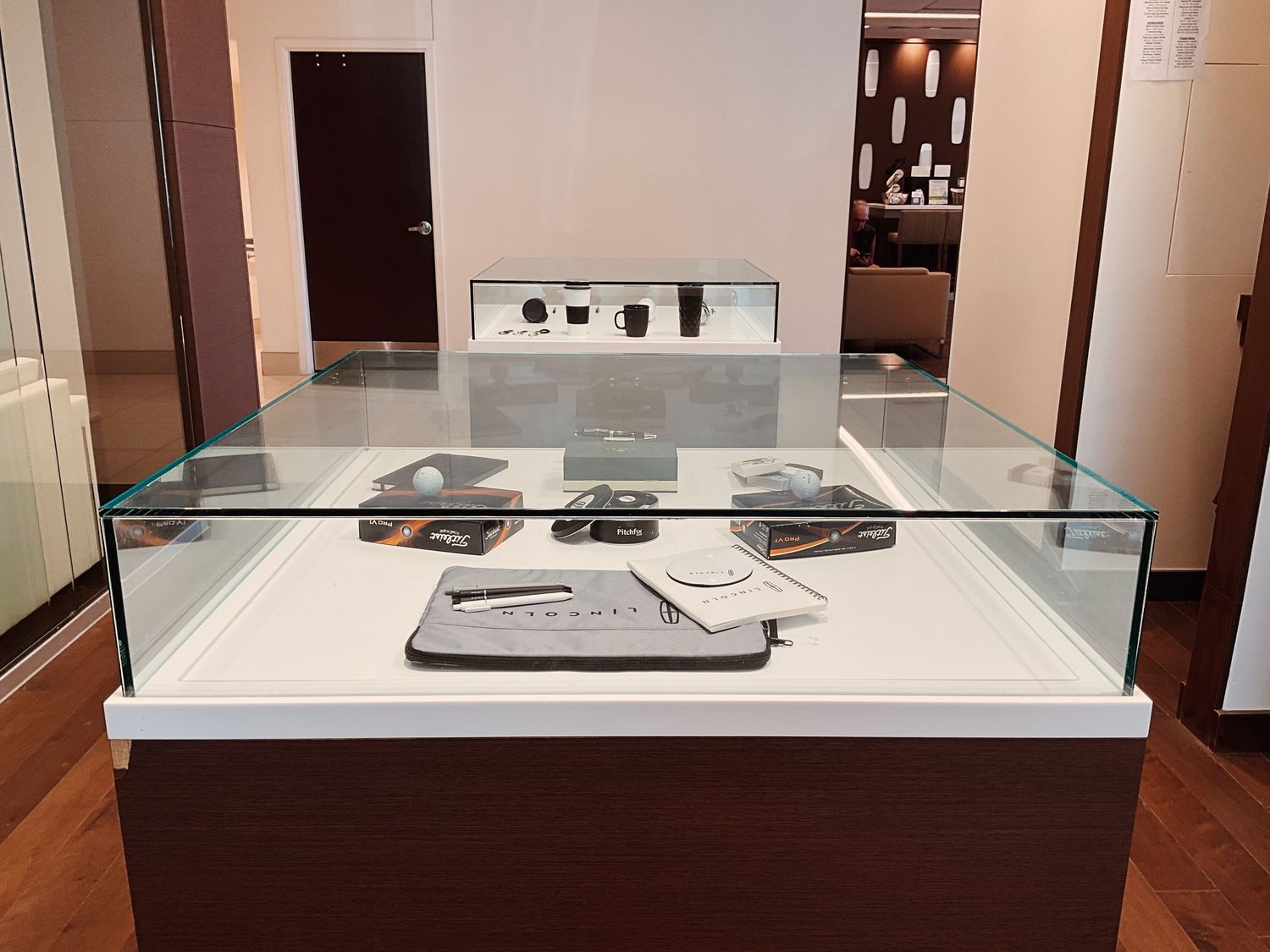Glass display case showcasing luxury accessories and watches in an elegant retail showroom.