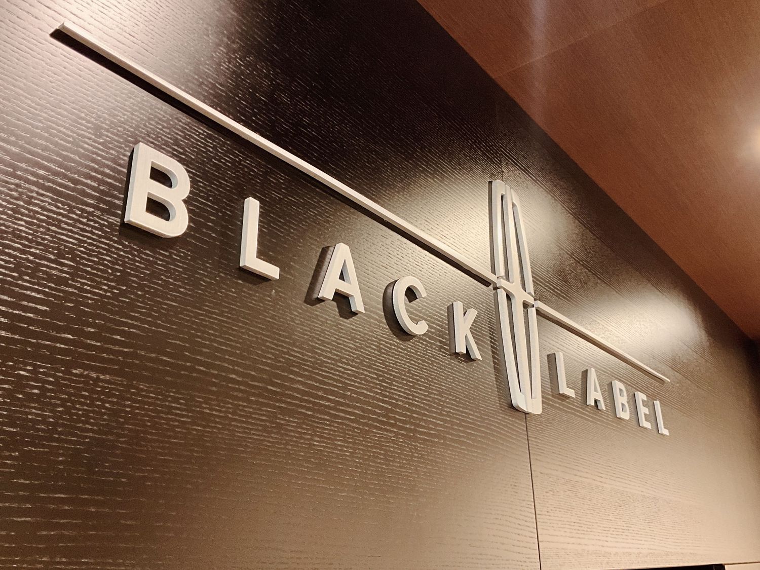 Black Label logo sign with sleek metallic letters on a dark textured wall, featuring a Lincoln emblem.