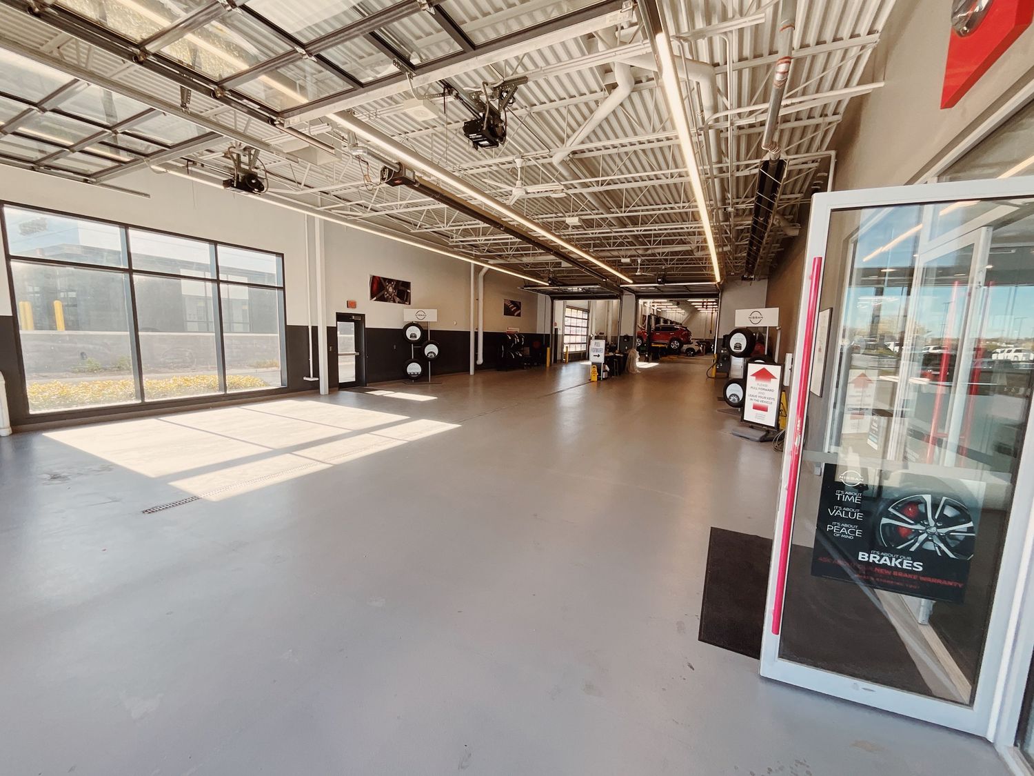 Spacious auto dealership showroom with polished gray floors, high ceilings, and large windows allowing natural light.
