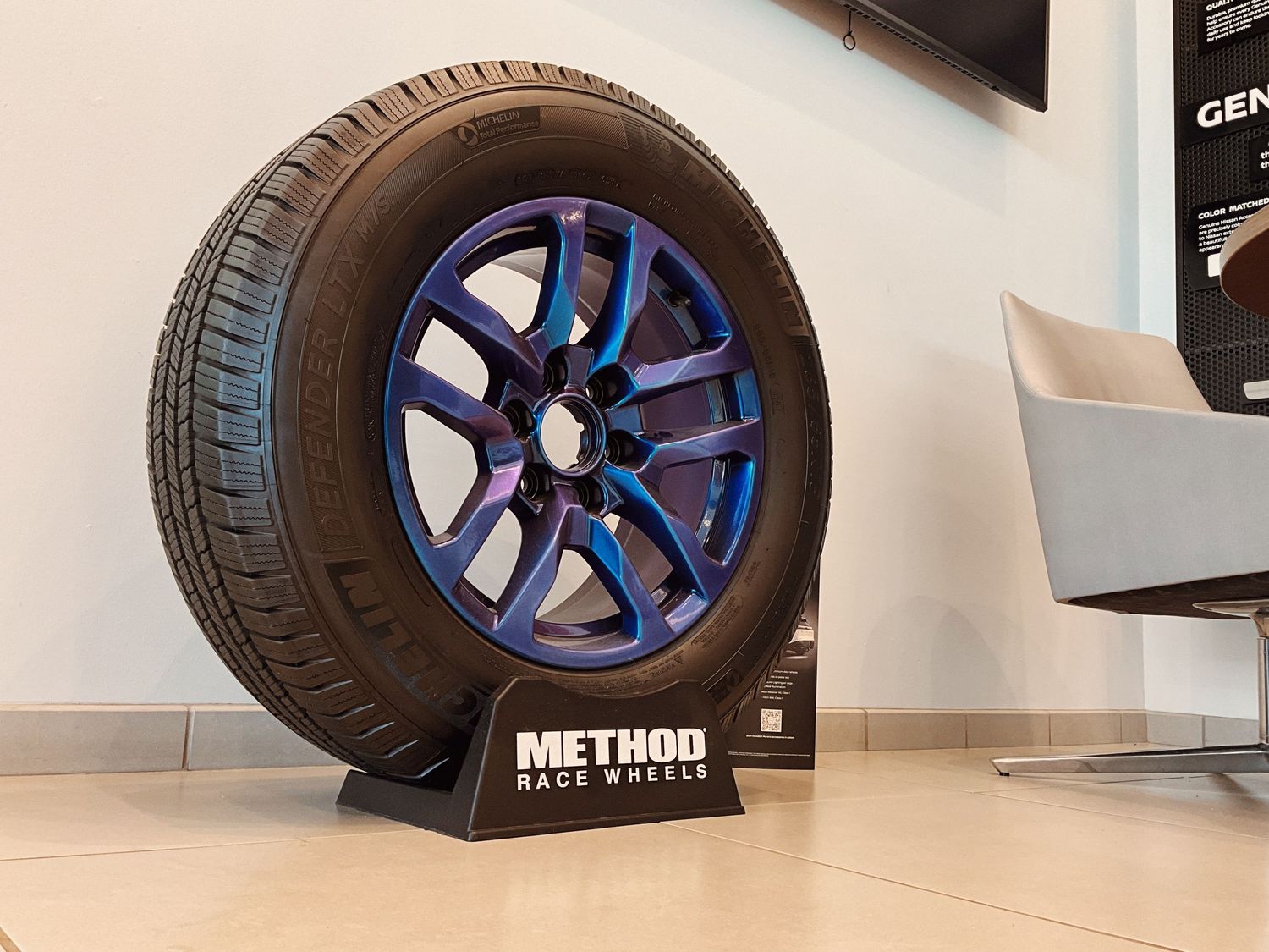 Method Race Wheels colorful blue and purple alloy wheel on display stand at an automotive showroom.