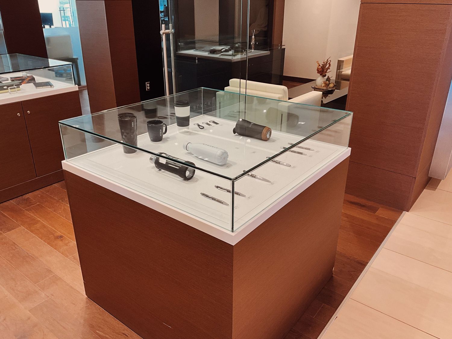 Glass display case showcasing luxury accessories and watches inside an elegant retail store with wood paneling.