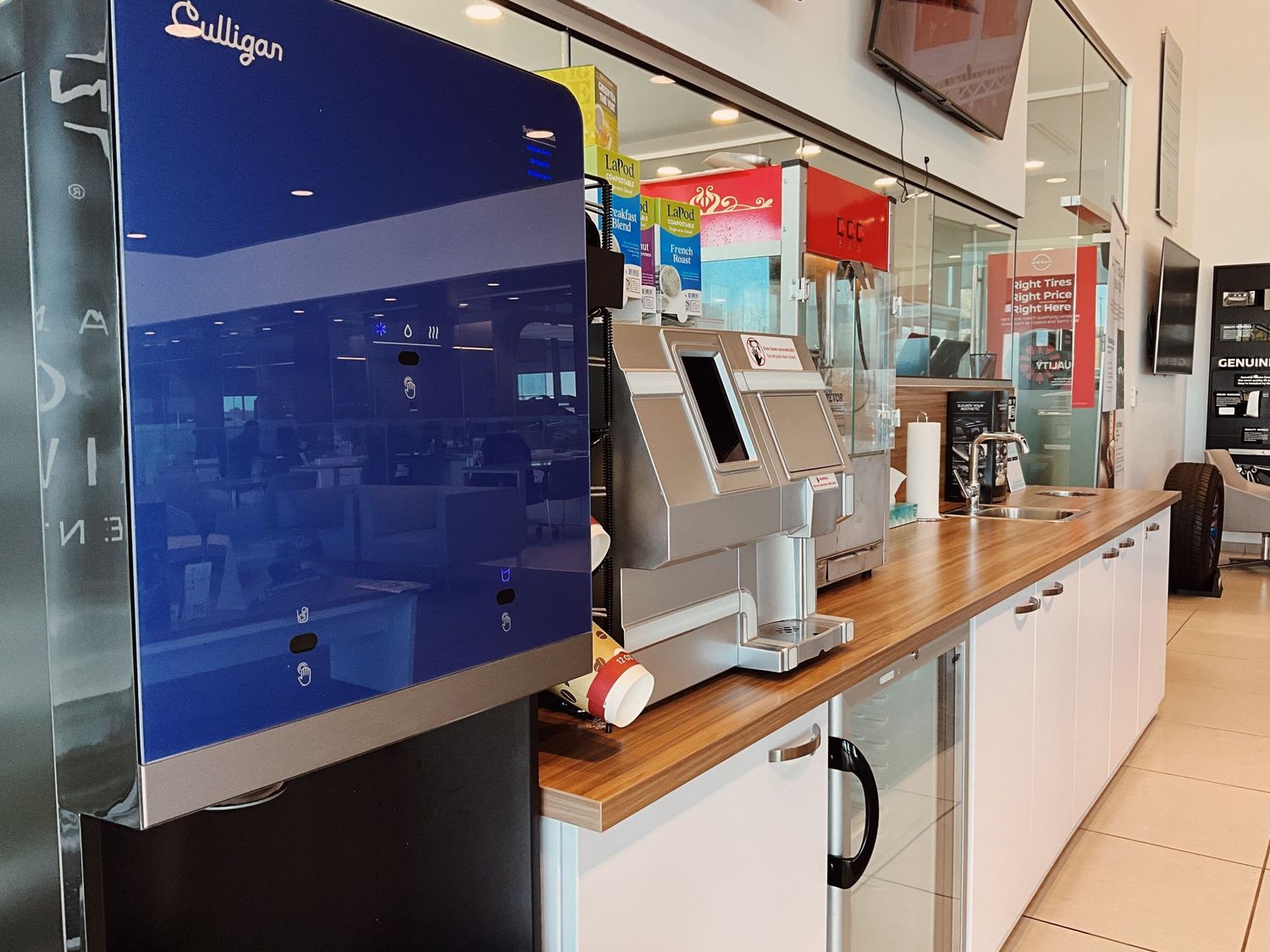 Modern self-checkout kiosks and Culligan water dispenser at a bright retail store service counter.