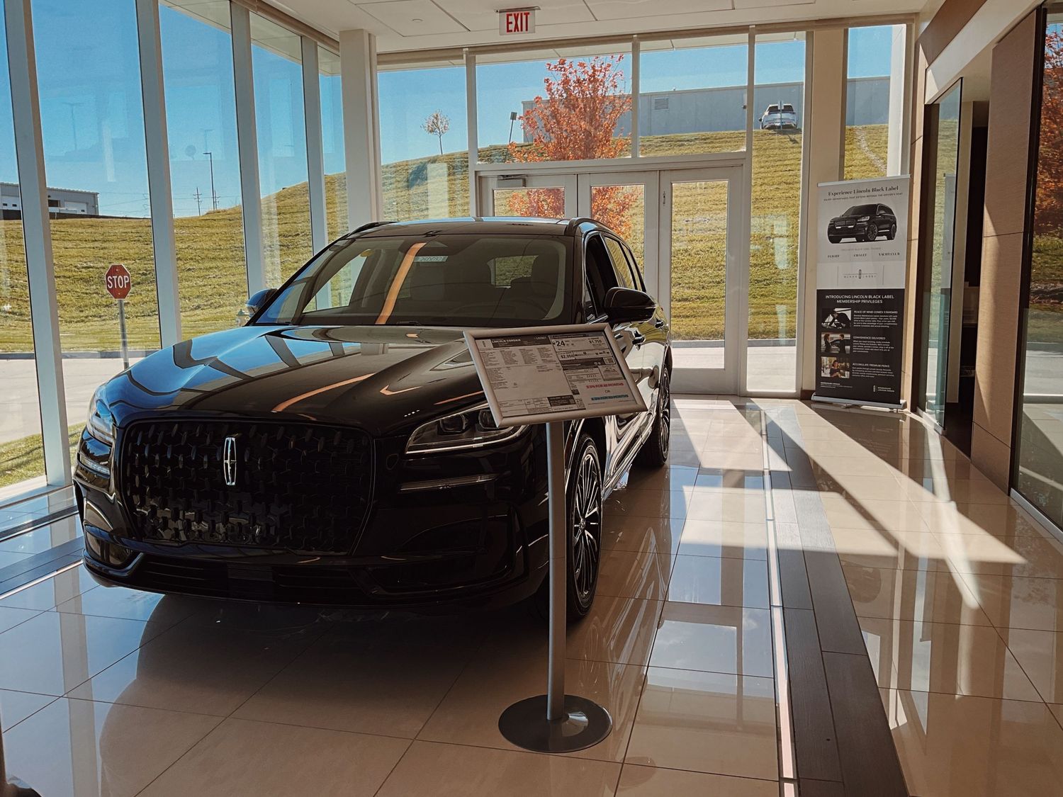 Black Lincoln SUV on display inside a bright car dealership showroom with large windows and polished floors.